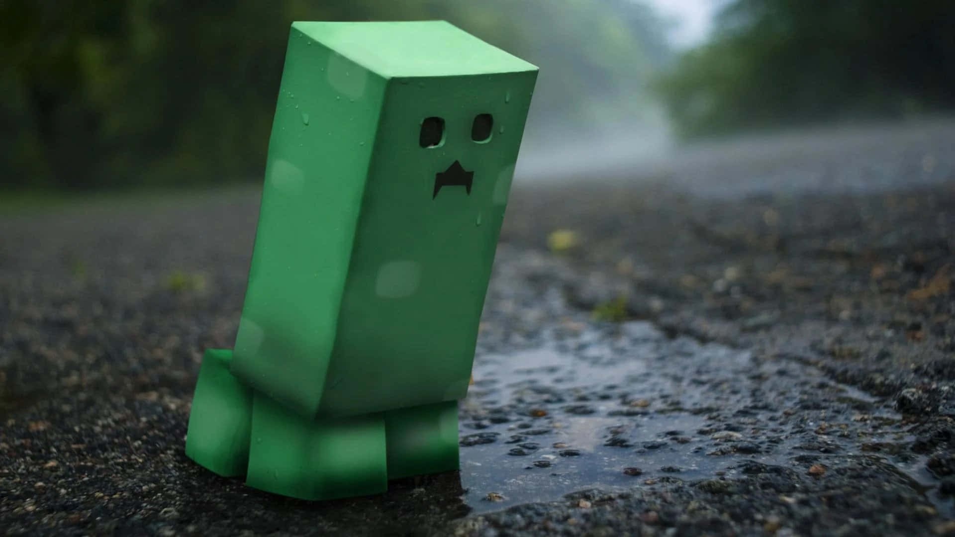 我的世界苦力怕 桌布 壁紙 — 一個綠色方塊狀的爬行者站在被雨水打濕的瀝青上，表面有水珠，背景是模糊的森林。