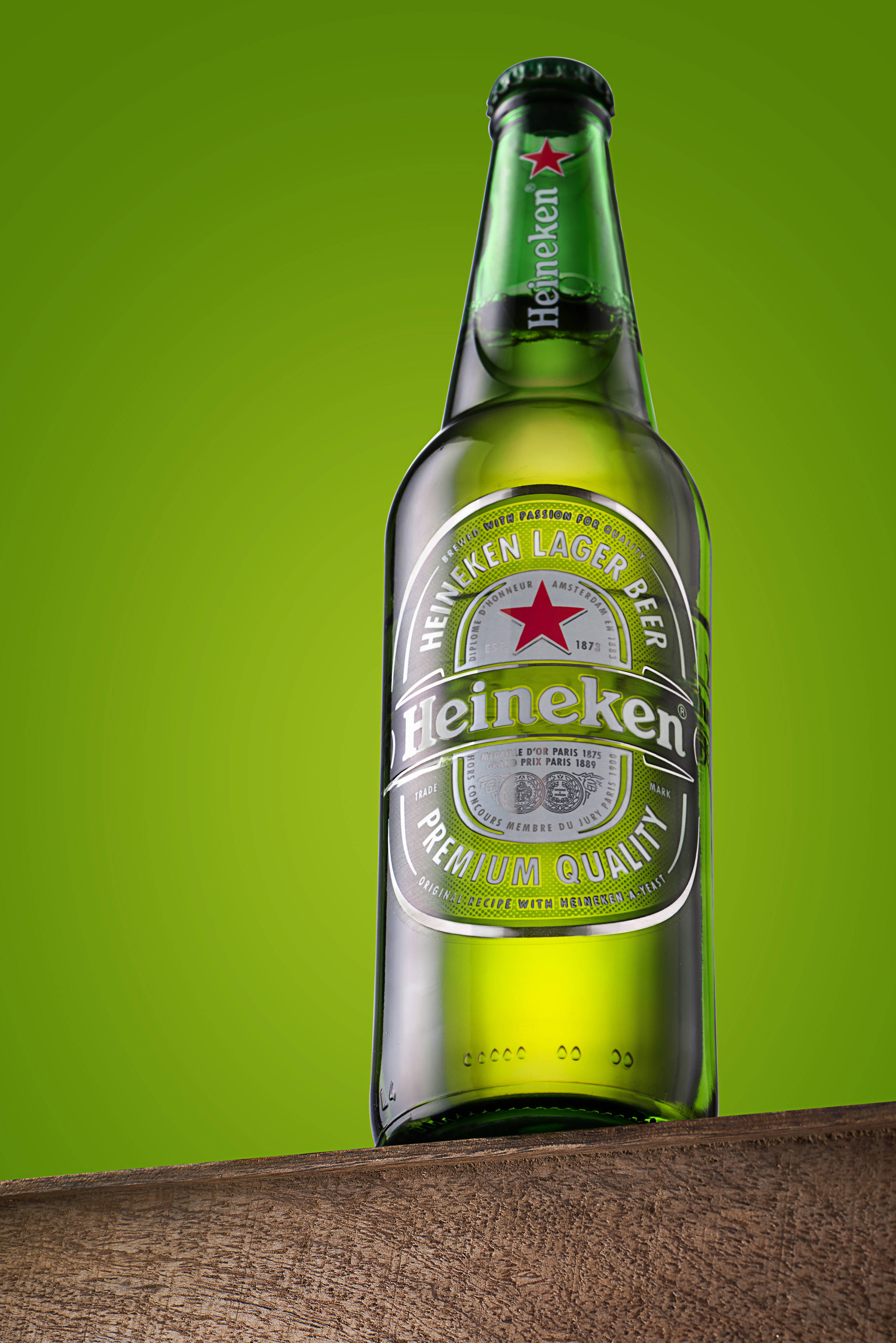 Beer 桌布 壁紙 — 一個綠色海尼根啤酒瓶直立於木質表面上，背景為充滿活力的萊姆綠色。