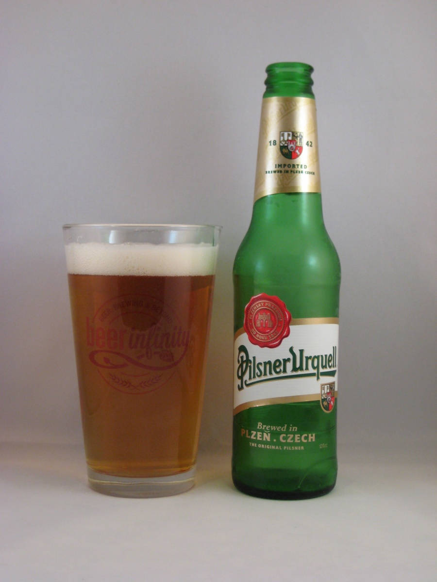 glass 桌布 壁紙 — 一個綠色的Pilsner Urquell啤酒瓶站在一杯有白色泡沫的金色啤酒旁邊，背景是純白色。