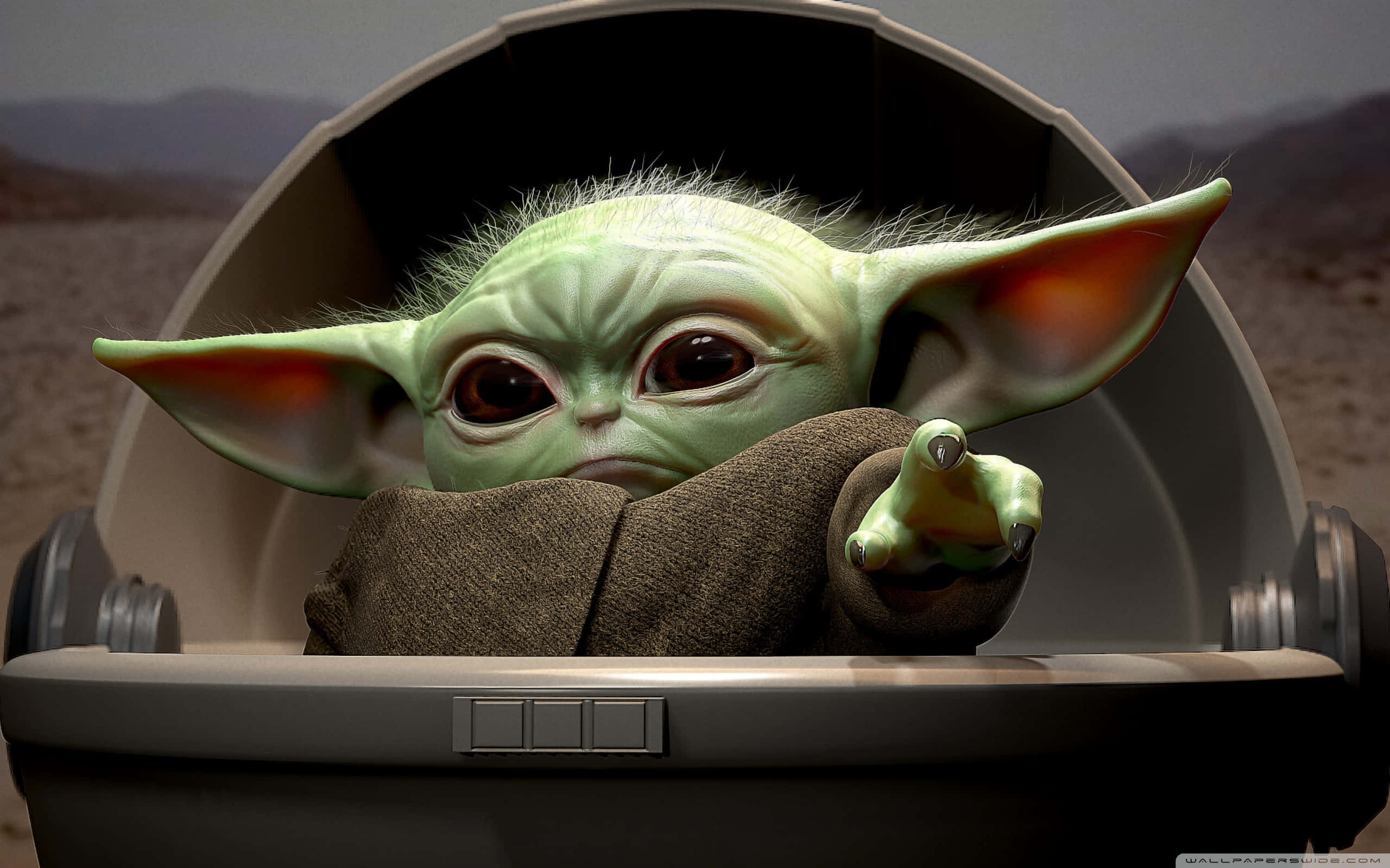 Baby Yoda Aesthetic 桌布 壁紙 — 一個綠色皮膚、大耳朵、眼神充滿表情的嬰兒尤達坐在太空船艙中，手指向前方。