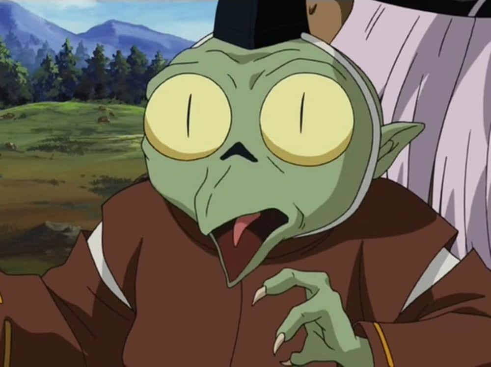 Inuyasha Jaken 桌布 壁紙 — 一個綠色皮膚的動漫角色，有著大大的黃色眼睛和驚訝的表情，站在有山脈背景的草地上。