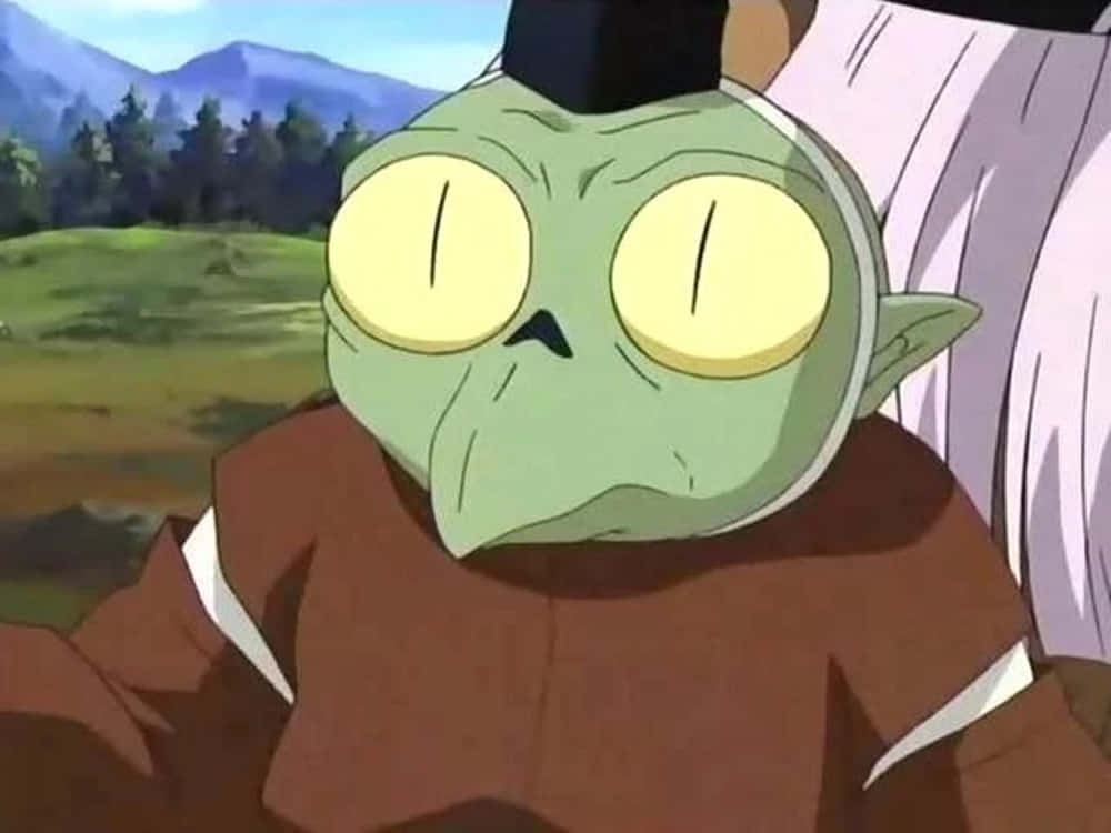 Inuyasha Jaken 桌布 壁紙 — 一個綠色皮膚的動漫角色特寫，有著大黃色眼睛和黑色髮髻，背景是山脈。