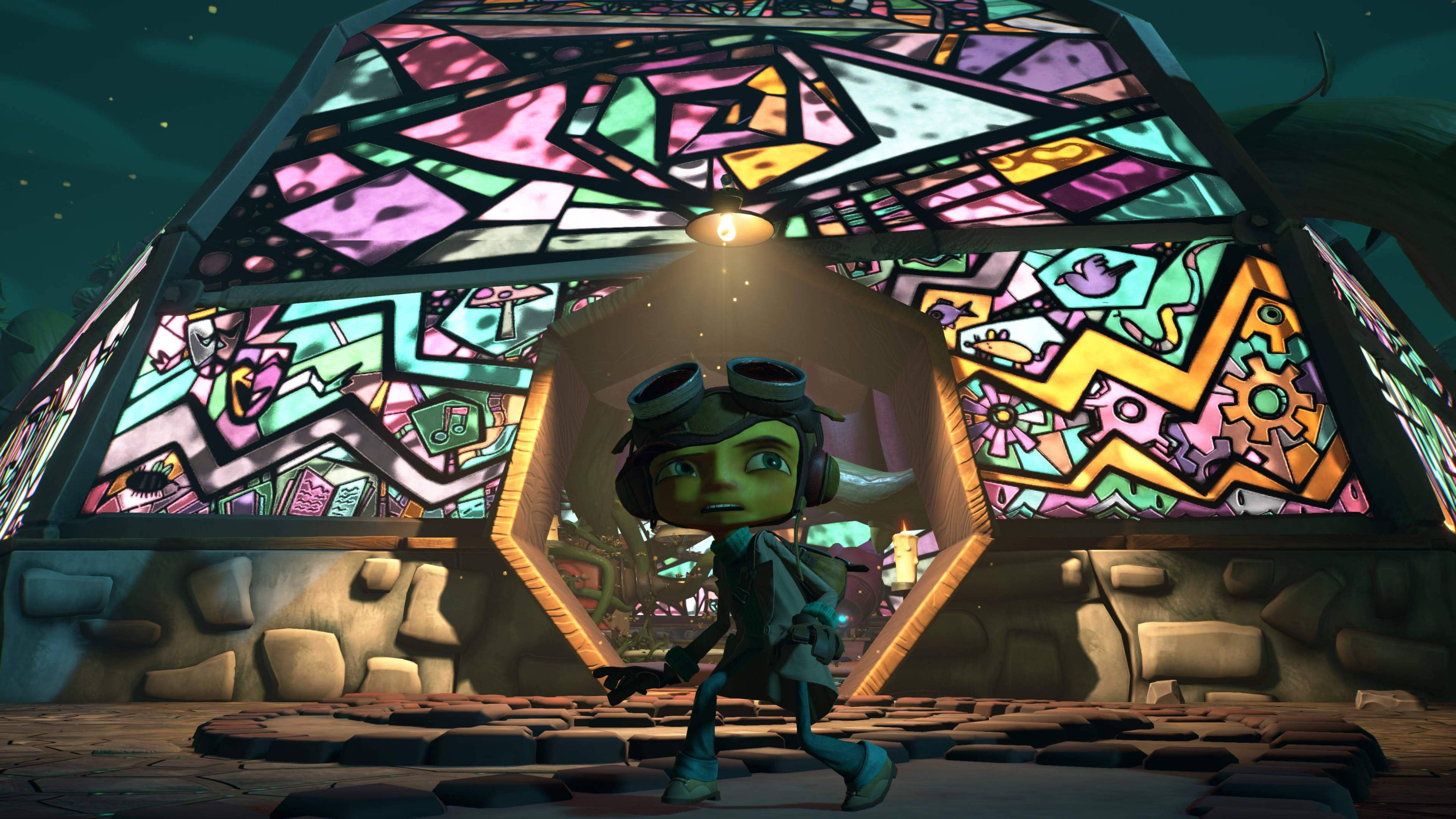 Psychonauts 桌布 壁紙 — 一個綠色皮膚的動畫角色戴著護目鏡，穿過神秘廢墟中發光的彩繪玻璃拱門。