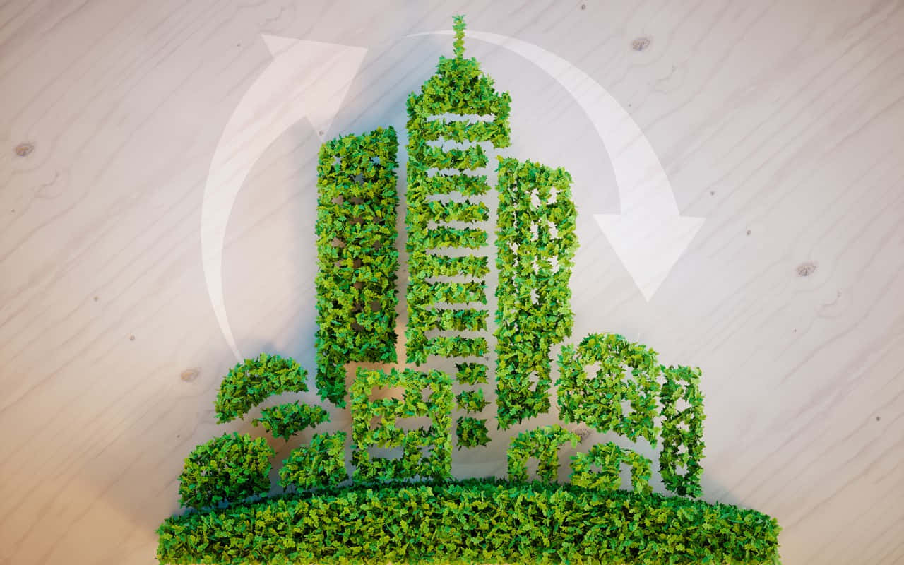 recycle 桌布 壁紙 — 一個綠色苔蘚雕塑，形狀像城市天際線，背後有一個回收標誌，放在木質表面上。