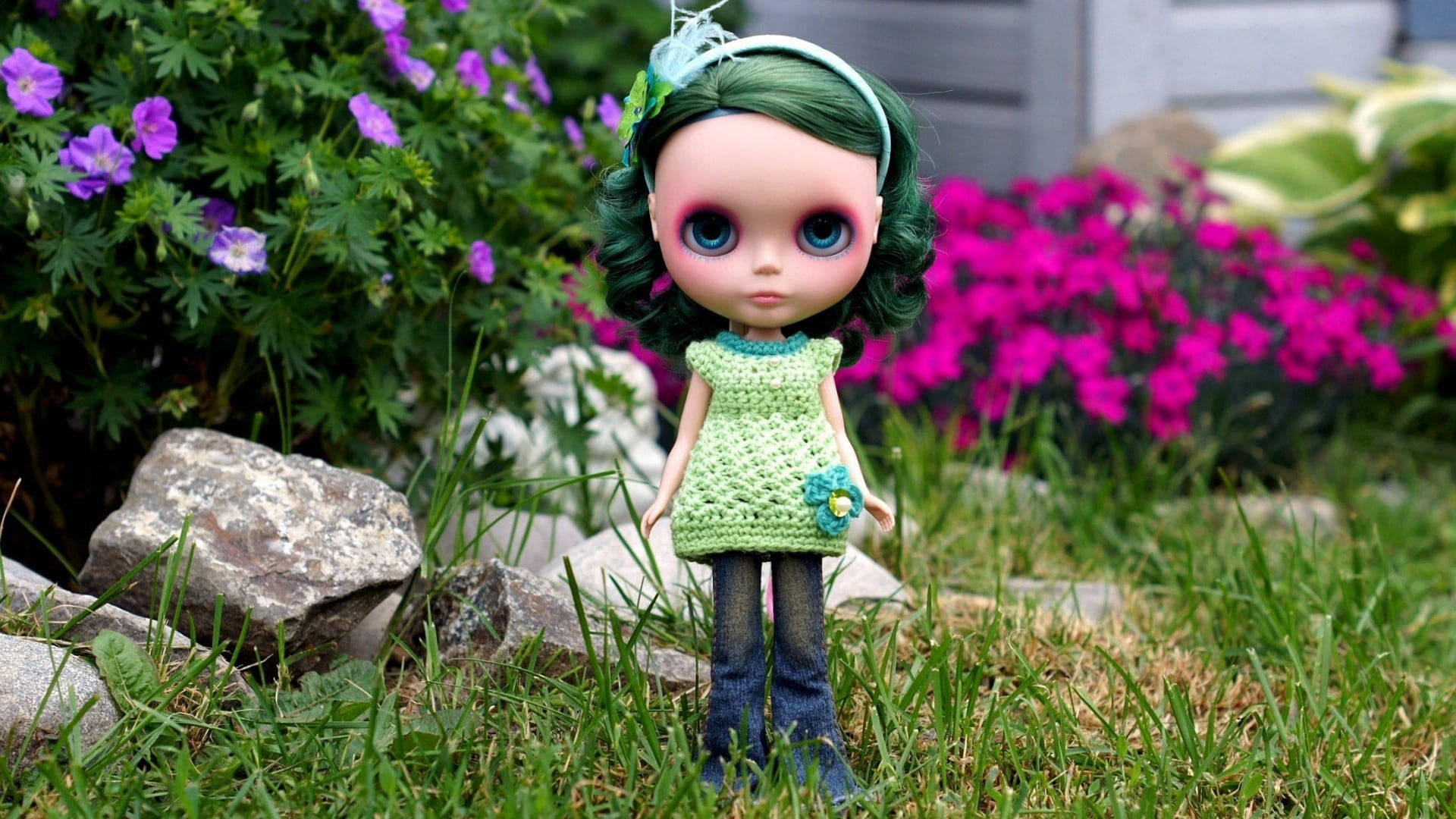 bratz 美學 桌布 壁紙 — 一個綠色頭髮、藍色眼睛的 Blythe 娃娃站在一個被紫色和粉紅色花朵包圍的草地花園中。