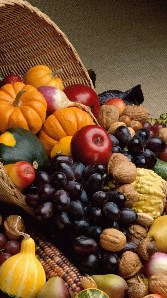 Fruits 桌布 壁紙 — 一個編織籃子，裝滿了充滿活力的秋季收穫產品，包括南瓜、葡萄、蘋果和堅果。