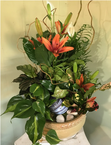 Garden 桌布 壁紙 — 一個編織籃子裡盛載著茂盛的花卉佈置，以淡色牆壁為背景，展現鮮豔的橙色百合和綠色葉子。