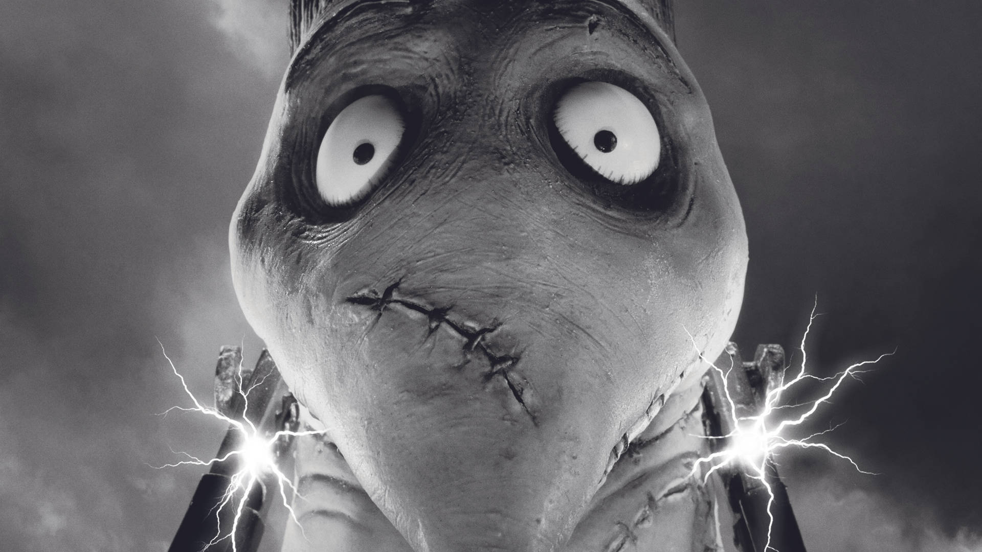 Frankenweenie 桌布 壁紙 — 一個縫合怪物，眼睛突出，雙手發出閃電，背景是暴風雨的天空。