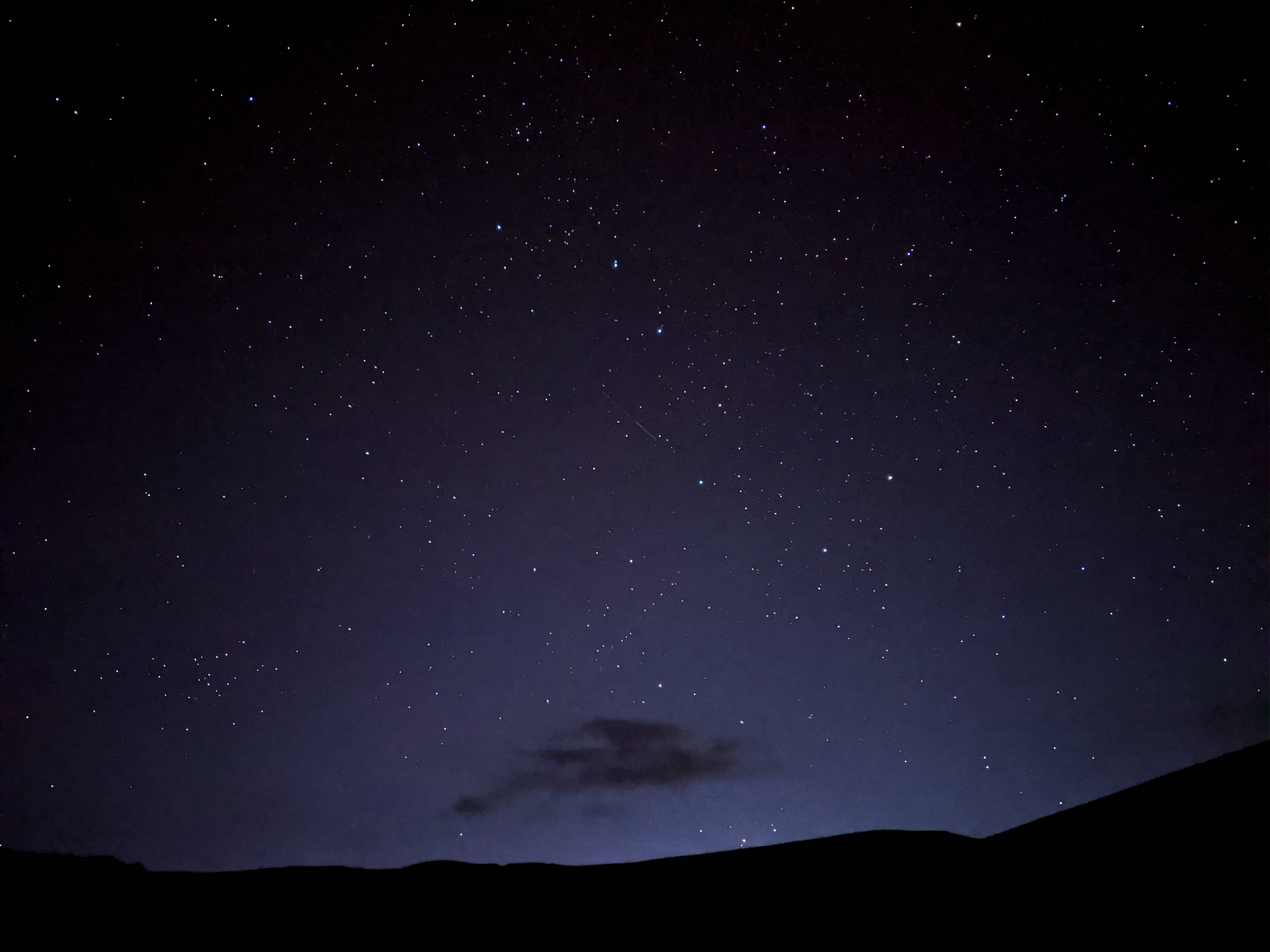 nasa 美學 桌布 壁紙 — 一個繁星點點的夜空，有一顆微弱的流星劃過黑暗的輪廓山丘和一朵雲。