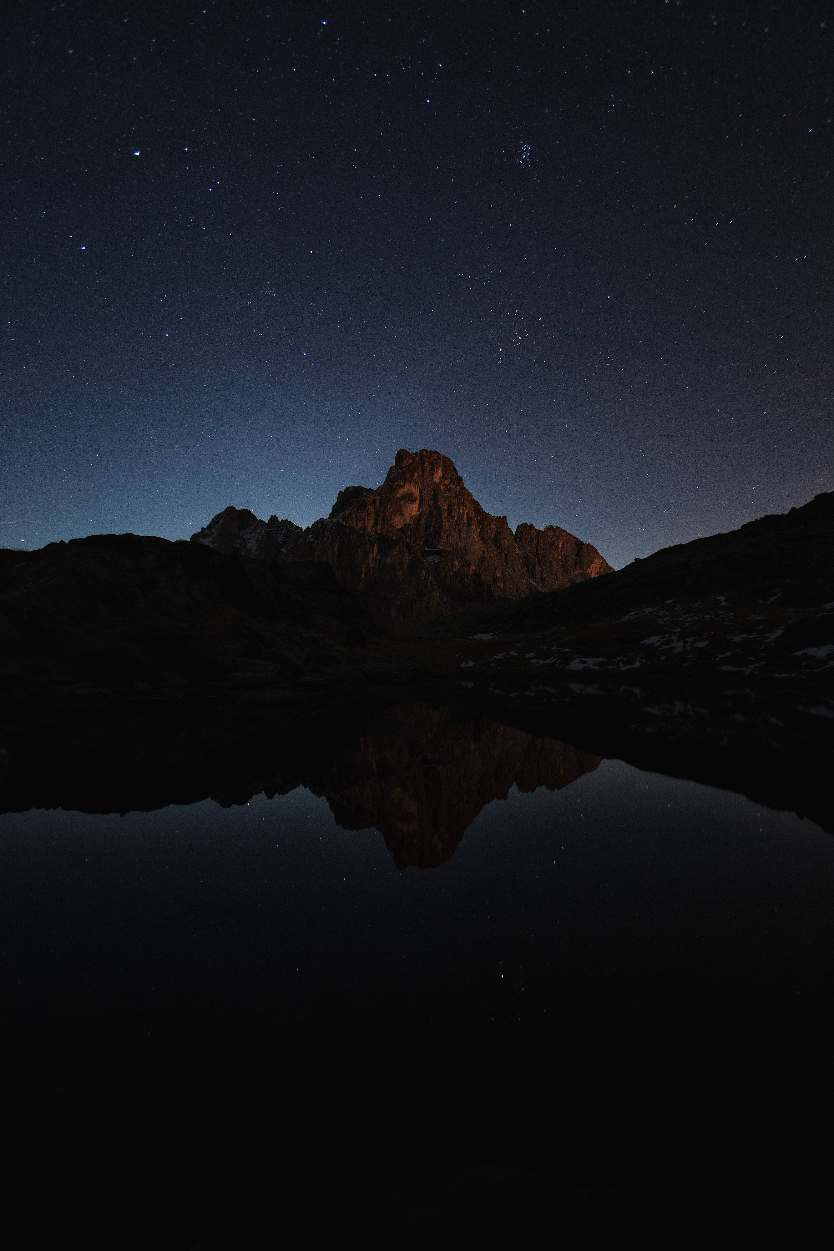 山景 桌布 壁紙 — 一個繁星點點的夜空完美地倒映在崎嶇山峰下平靜的山湖中。