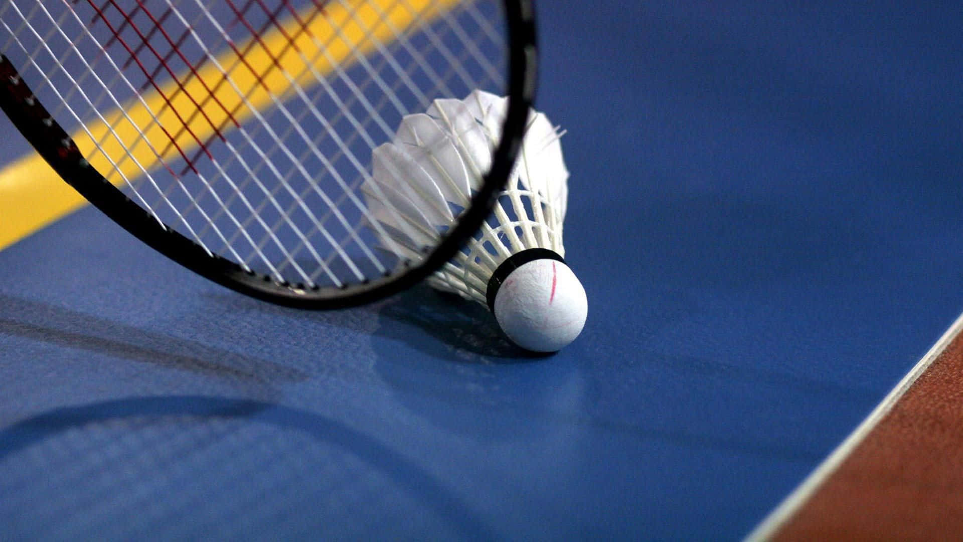 HD Badminton 桌布 壁紙 — 一個羽毛球拍和羽毛球在藍色球場上的特寫，球場有黃色界線。