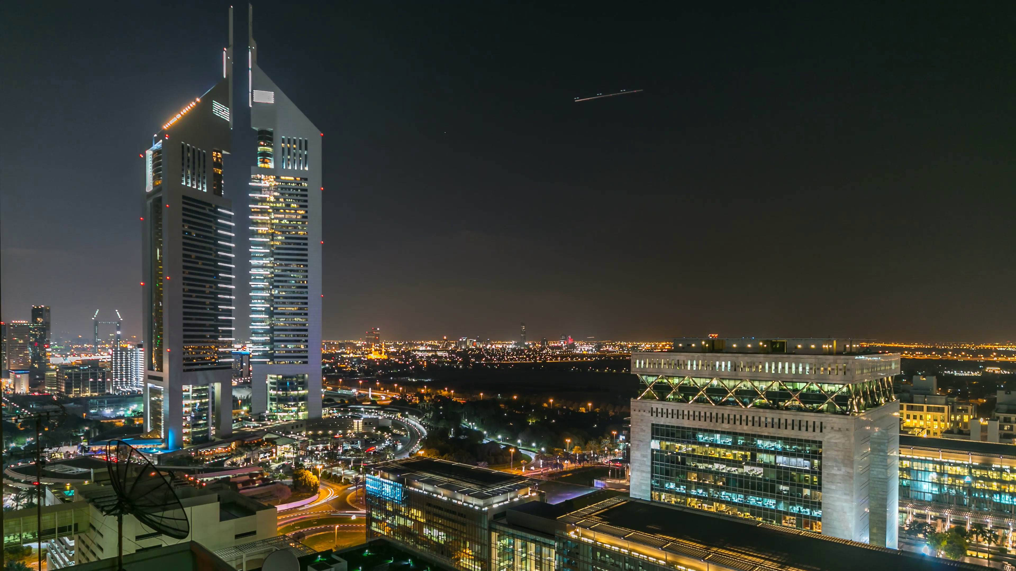 Arab 桌布 壁紙 — 一個耀眼的夜景城市景觀，特色是有一座高聳的摩天大樓，窗戶發光，下方車流形成光帶。