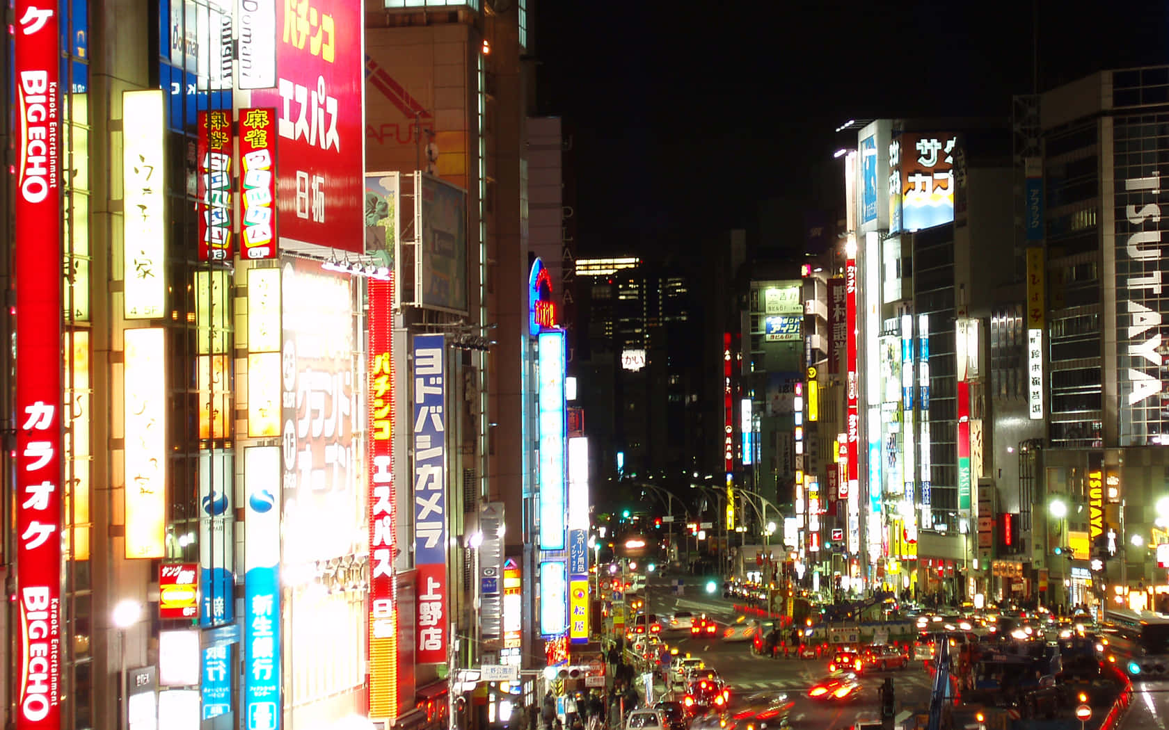 桌布 壁紙 — 一個耀眼的夜景城市景觀，霓虹燈閃爍的摩天大樓和熙熙攘攘的街道，充滿了發光的招牌和交通。