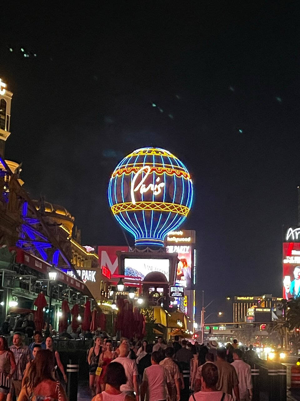 Hot Air Balloon 桌布 壁紙 — 一個耀眼的巴黎拉斯維加斯霓虹熱氣球招牌，在充滿明亮燈光和擁擠人群的夜街上閃耀。