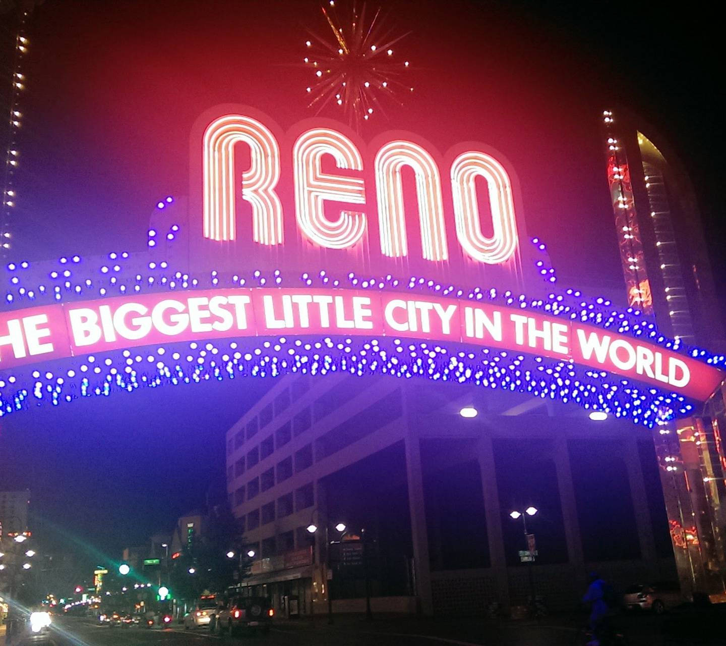 Arch 桌布 壁紙 — 一個耀眼的霓虹燈牌，上面寫著「RENO THE BIGGEST LITTLE CITY IN THE WORLD」，在夜晚發光，上方有煙火綻放。