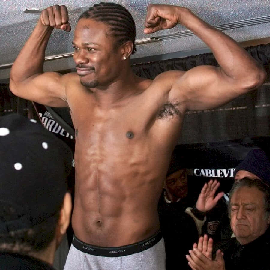 Boxing 桌布 壁紙 — 一個肌肉男在更衣室赤裸上身彎曲手臂，旁邊有人觀看。