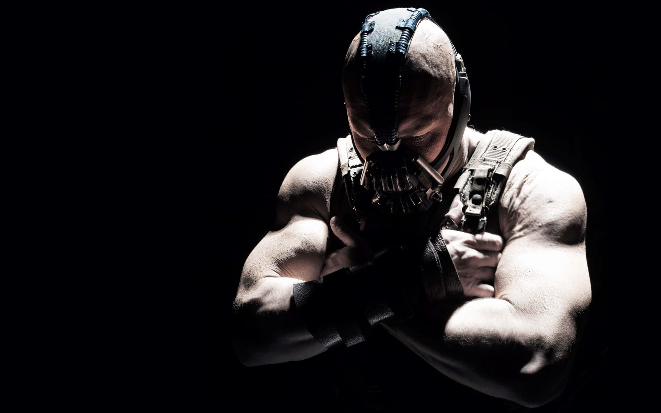 bane 桌布 壁紙 — 一個肌肉發達、戴著蝙蝠面具的男人在黑暗中交叉雙臂站立，被戲劇性的聚光燈照亮。