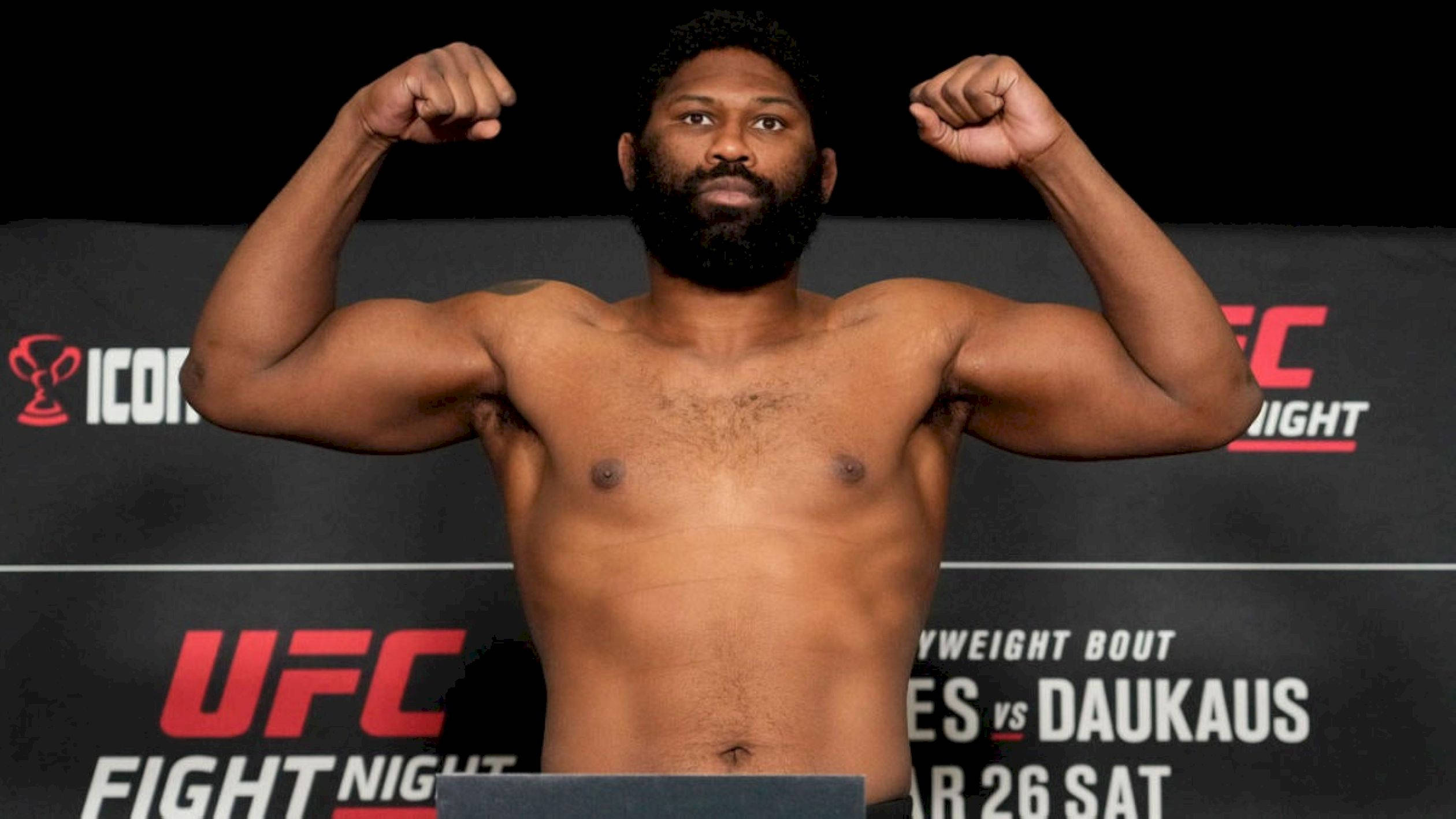MMA 桌布 壁紙 — 一個肌肉發達、留鬍子的拳手在明亮的攝影棚燈光下，於 UFC 稱重活動中赤裸上身彎曲手臂。