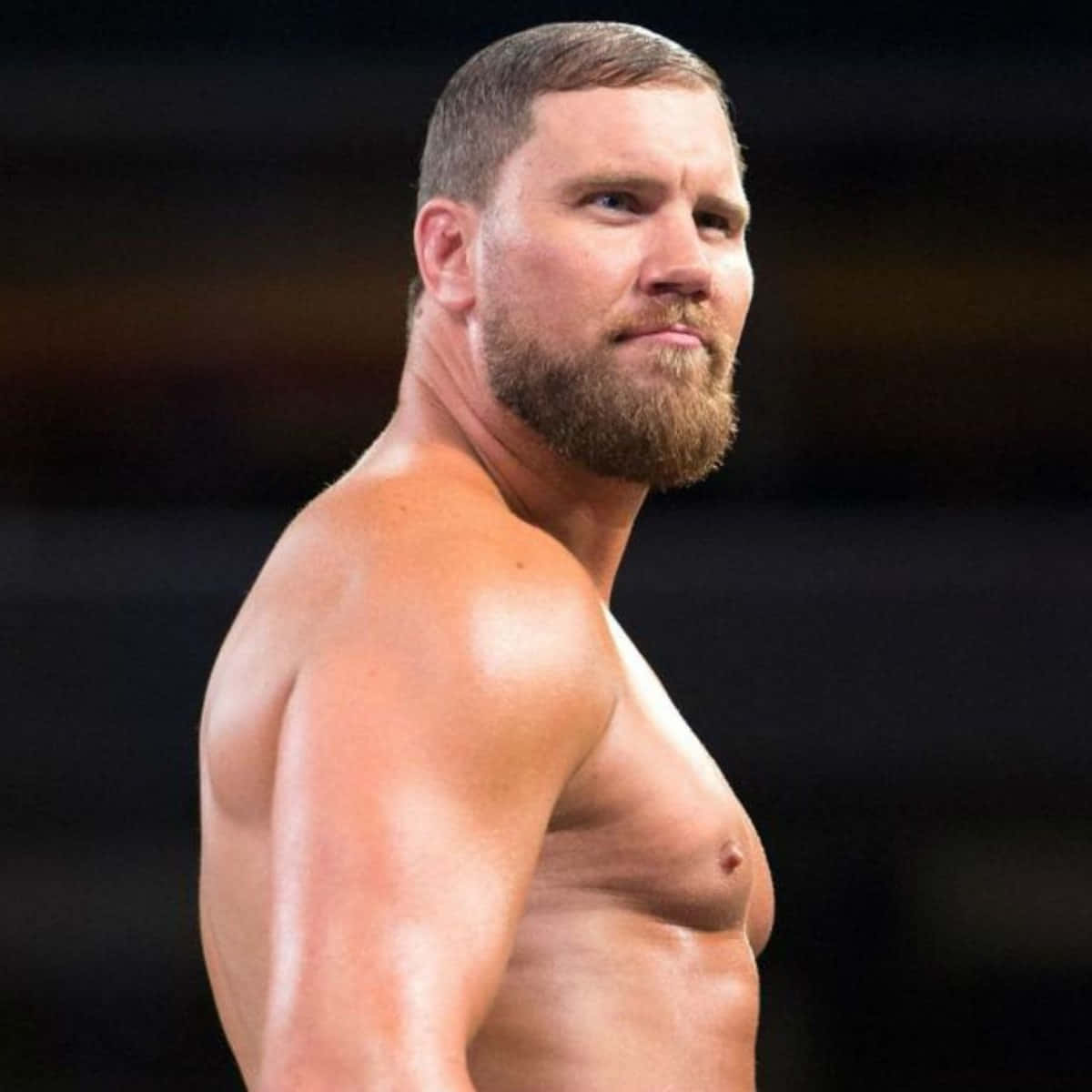 WWE 桌布 壁紙 — 一個肌肉發達、留鬍子的男人在摔角擂台上，汗水在皮膚上閃閃發光，他正凝視著鏡頭。