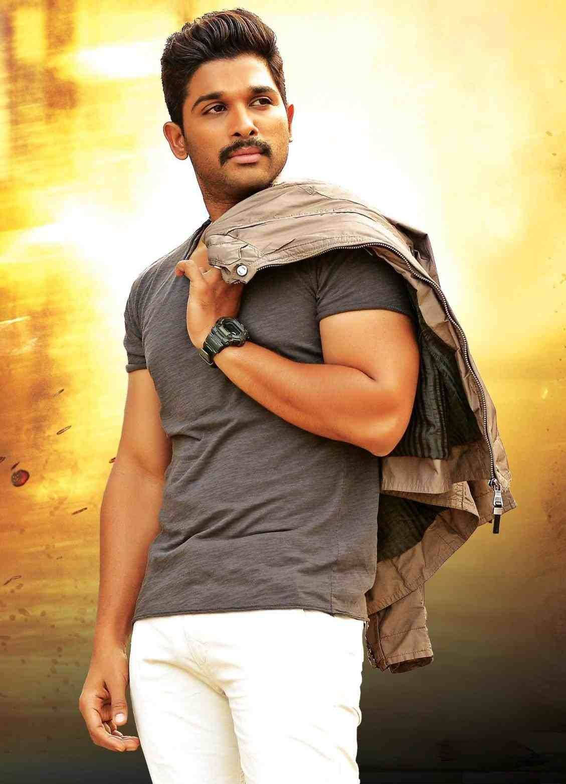 Allu Arjun 桌布 壁紙 — 一個肌肉發達、留鬍子的男人穿著灰色T恤和白色褲子，肩上搭著一件外套，背景是金色紋理。