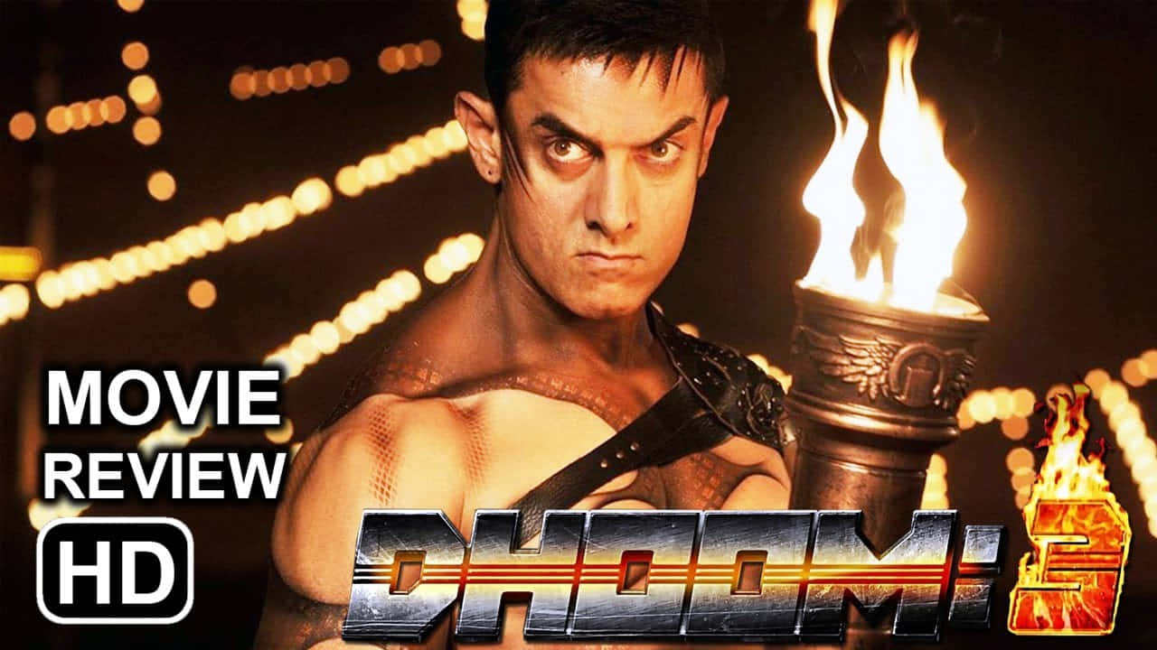 Aamir Khan 桌布 壁紙 — 一個肌肉發達、眼神銳利的男人，手持燃燒的火把，背景是發光的燈串。