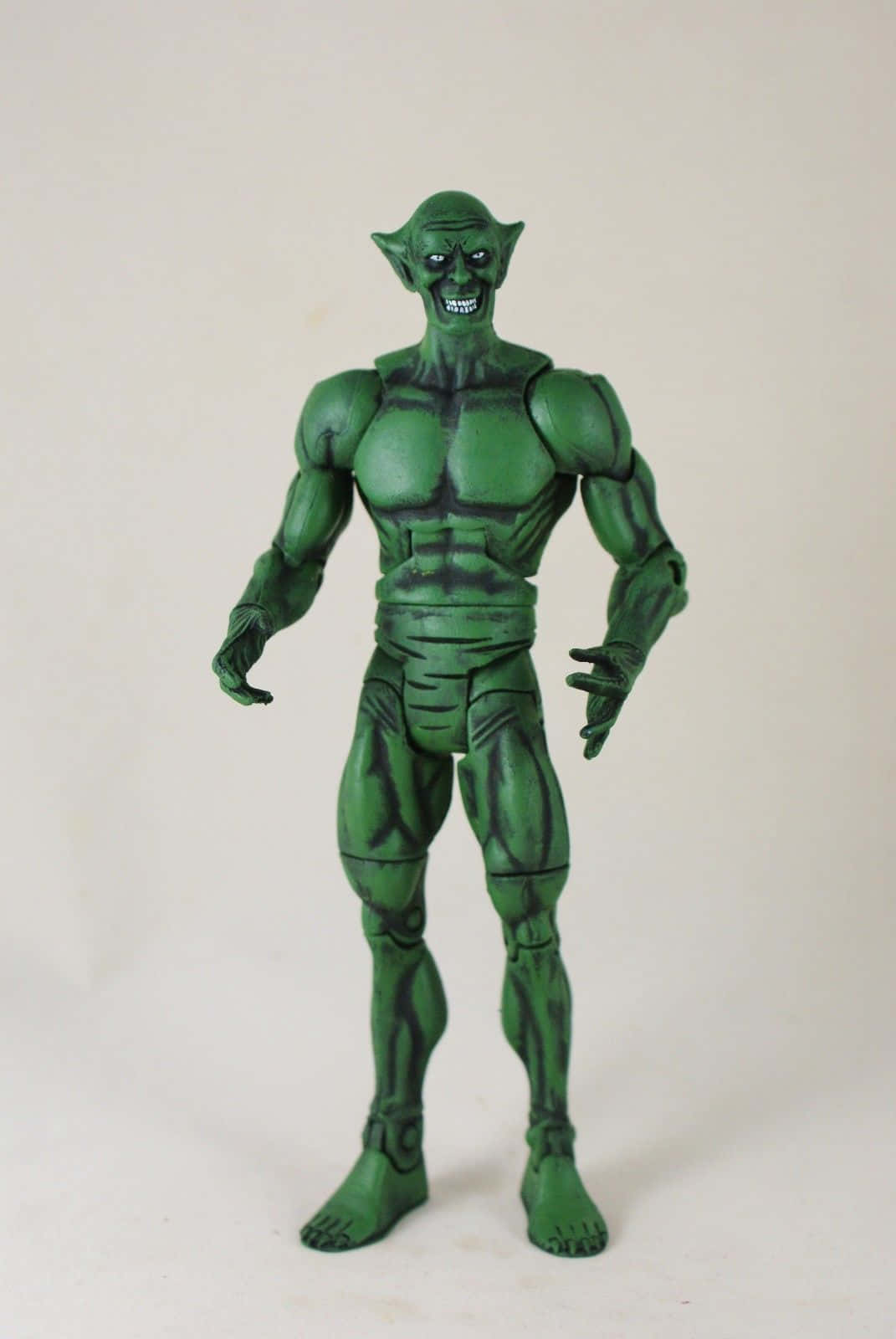 The Jackal 桌布 壁紙 — 一個肌肉發達、綠色皮膚的哥布林動作人偶，有著尖耳朵和猙獰的笑容，站在純白色背景前。