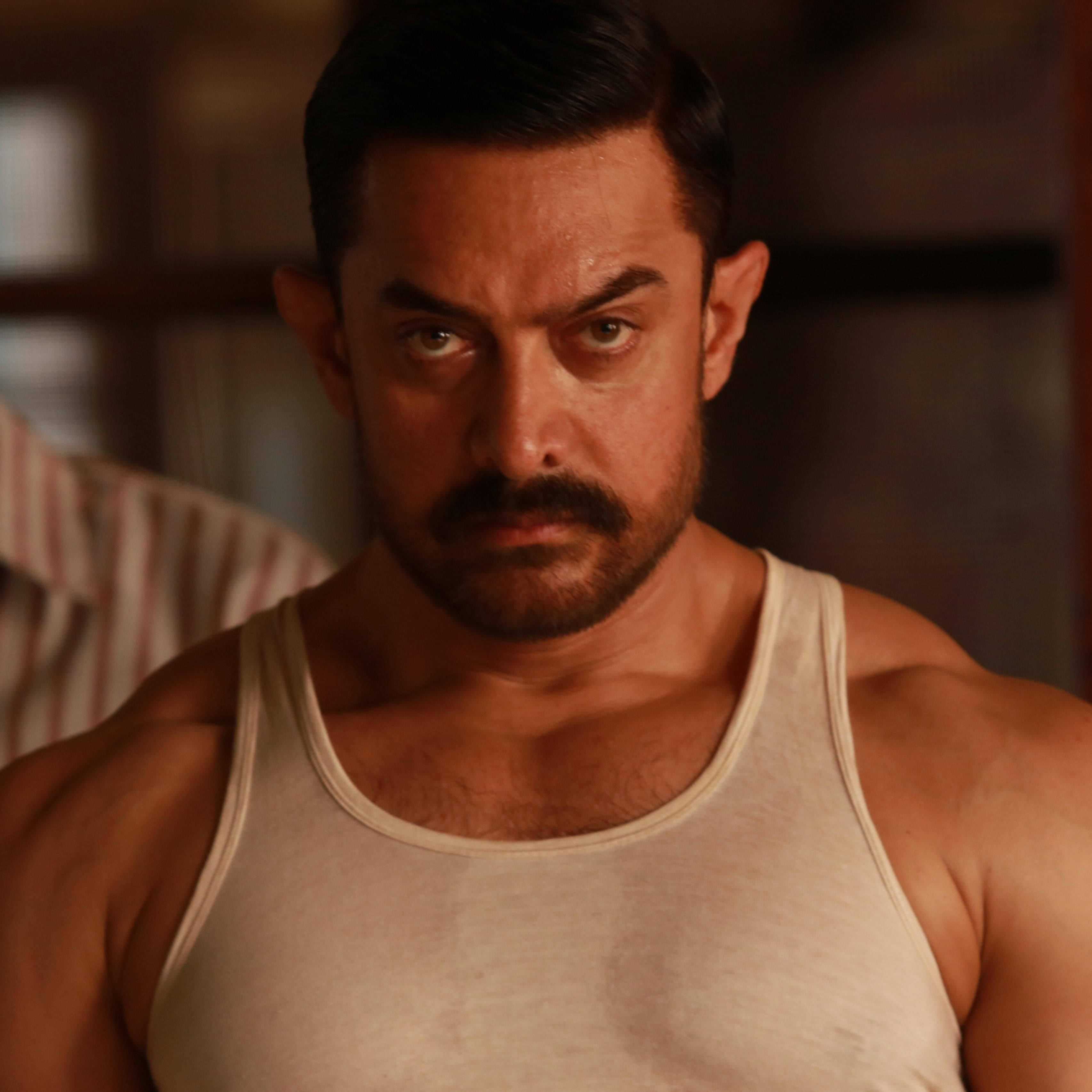 Aamir Khan 桌布 壁紙 — 一個肌肉發達、表情嚴肅的男人在溫暖的室內環境中凝視著。