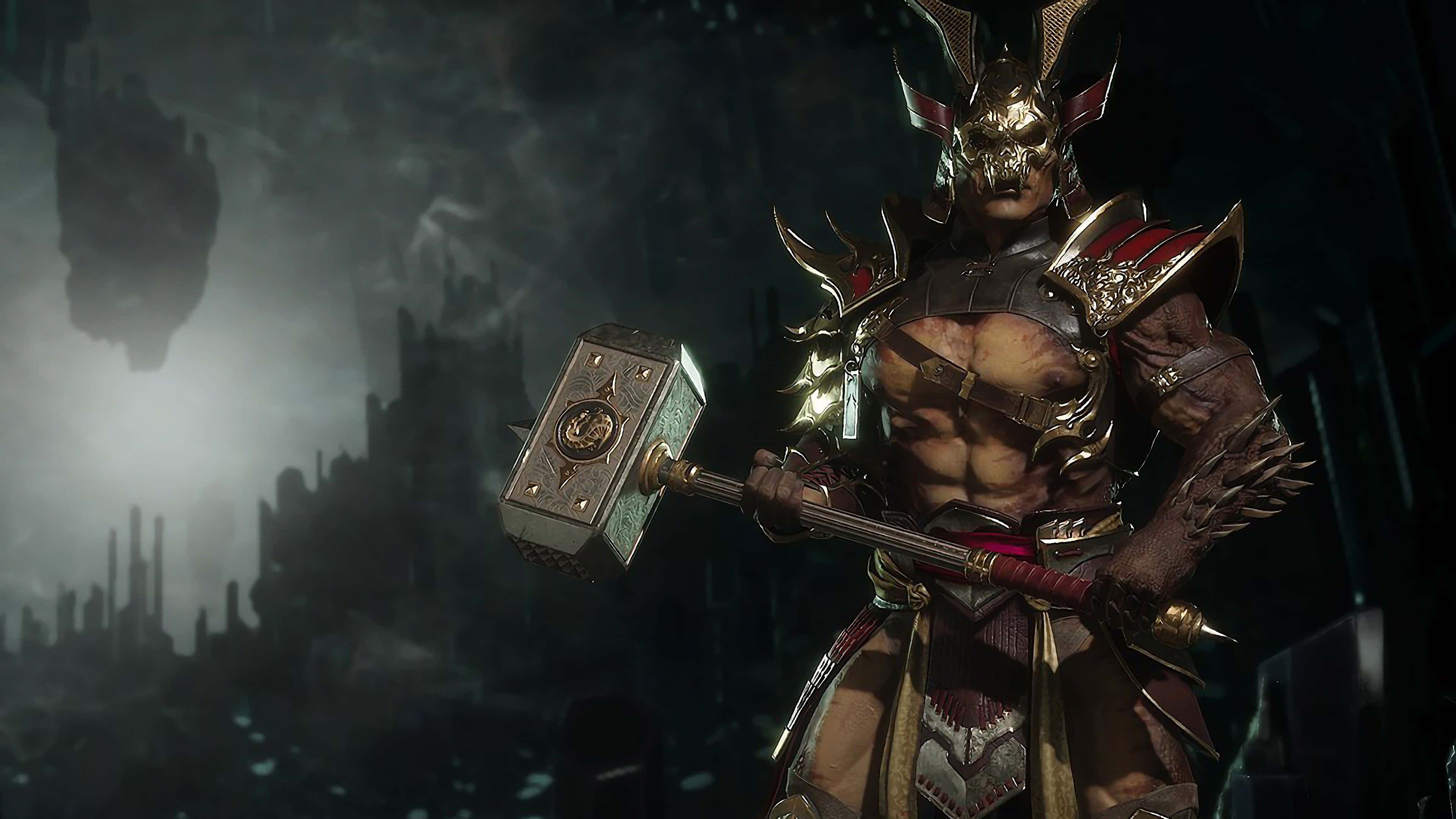 Mortal Kombat Shao Kahn 桌布 壁紙 — 一個肌肉發達、身穿盔甲、頭戴骷髏頭盔的戰士，在黑暗的廢墟城市景觀中揮舞著一把巨大的錘子。