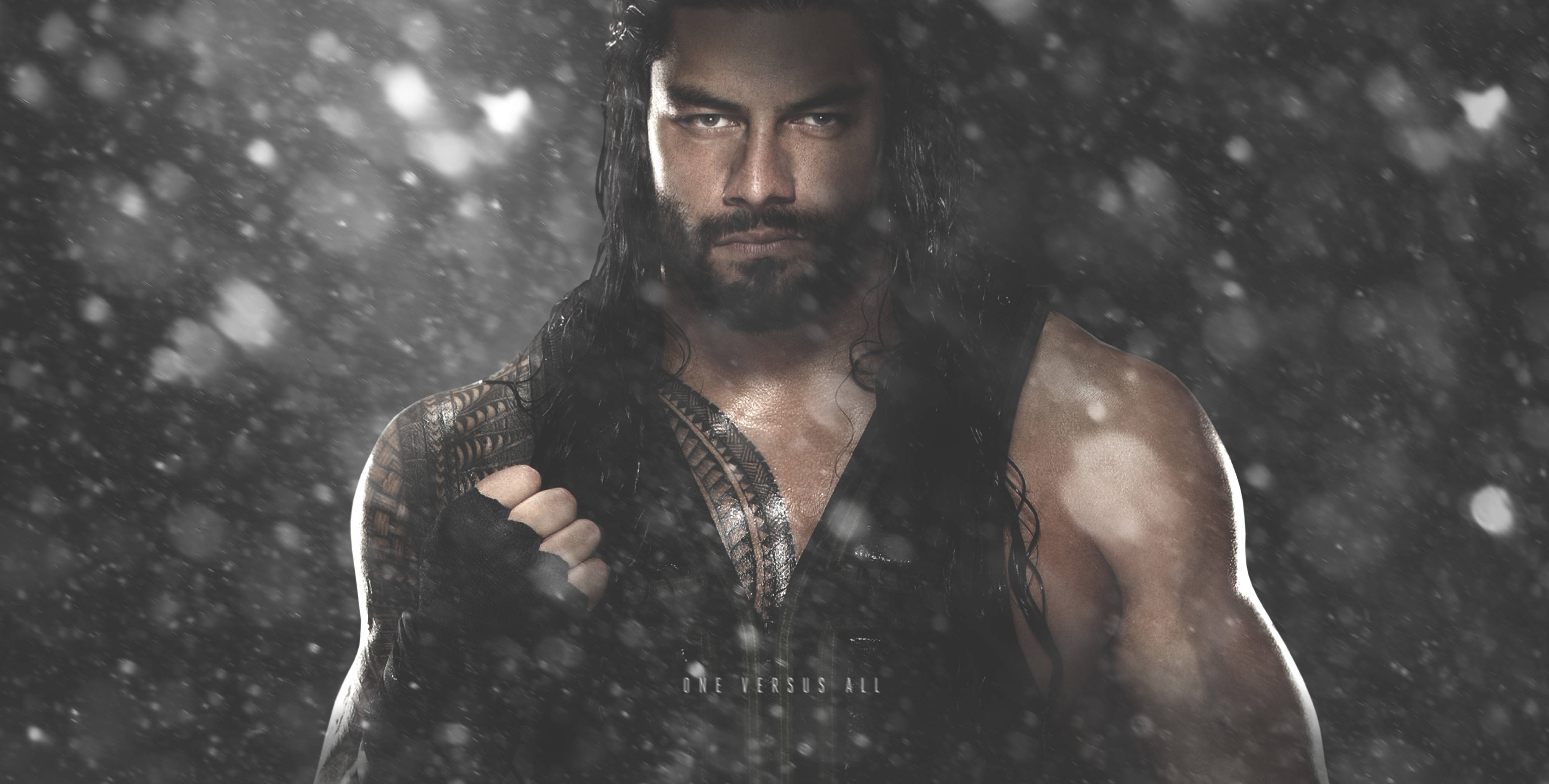 Roman 桌布 壁紙 — 一個肌肉發達、長黑髮和鬍鬚的男人在戲劇性燈光下，挑釁地站在飄落的雪中。