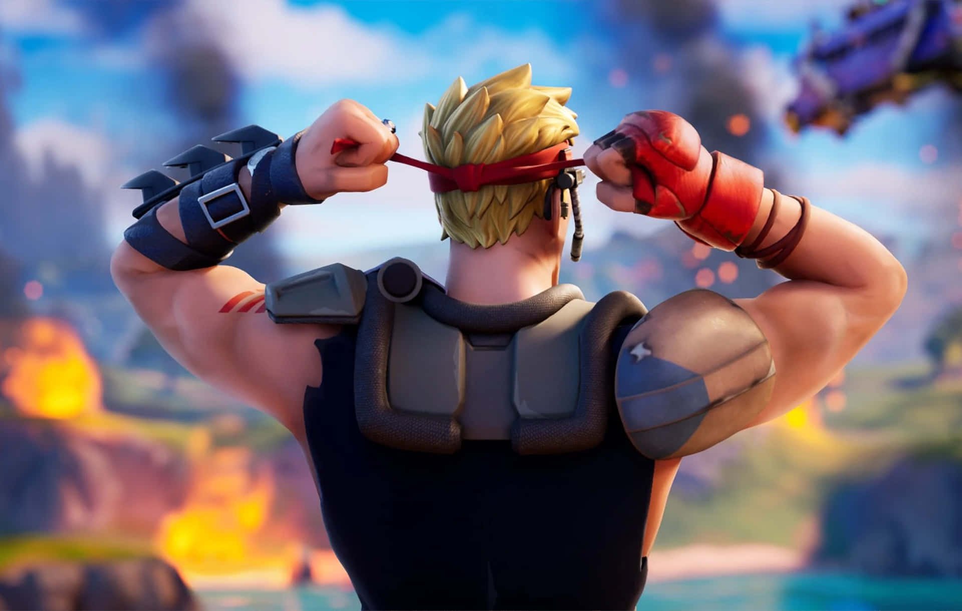 Building Game 桌布 壁紙 — 一個肌肉發達的Fortnite角色，留著尖刺金髮，綁著紅色頭帶，面對熾熱的戰場。