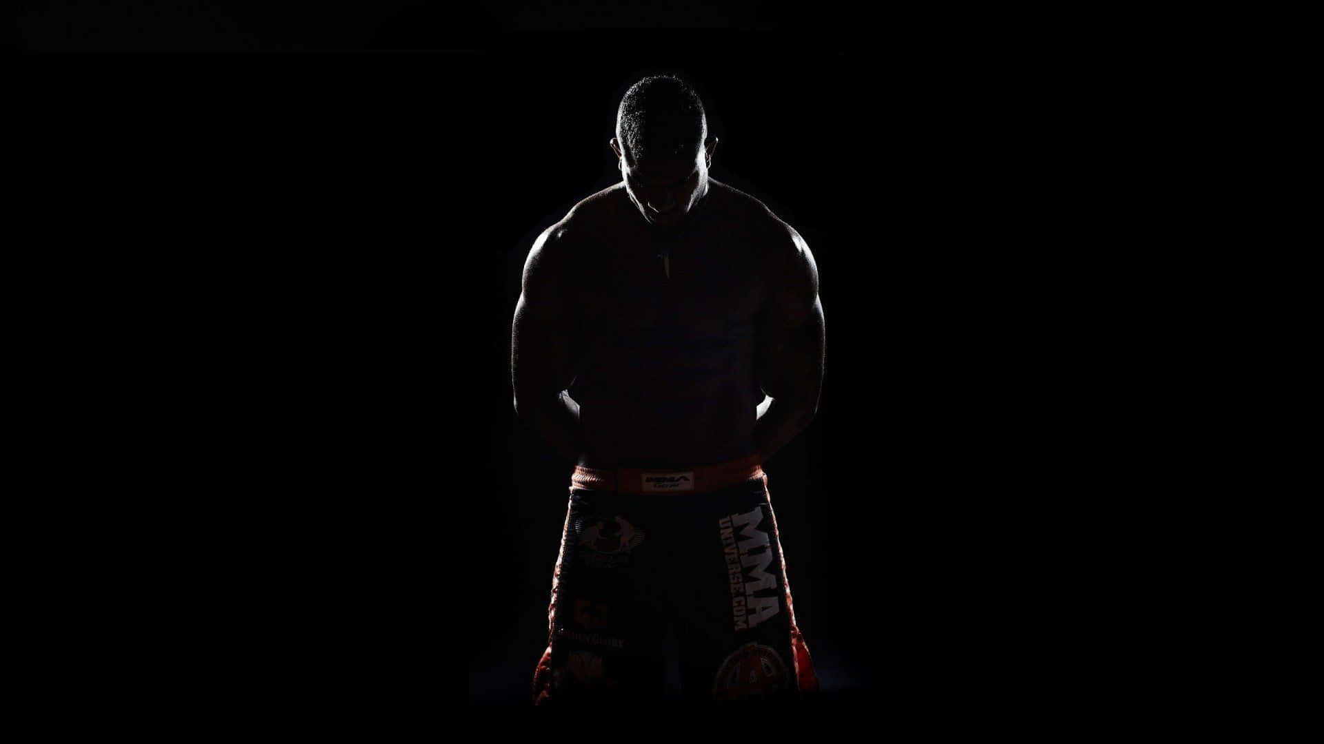 Boxing 桌布 壁紙 — 一個肌肉發達的MMA拳手以剪影形式站在黑色背景前，短褲上有微弱的紅色飾邊。