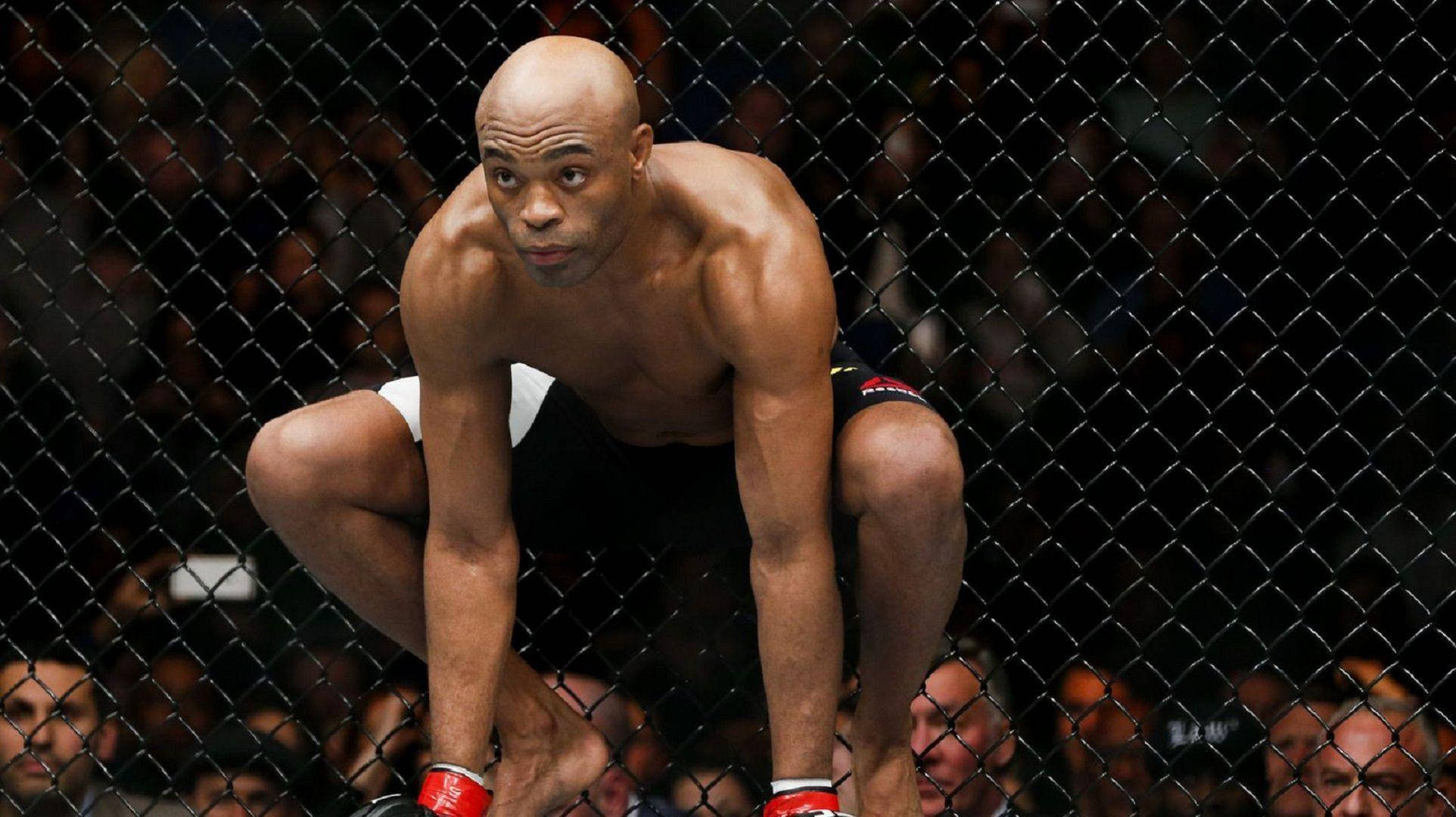 UFC 桌布 壁紙 — 一個肌肉發達的光頭戰士在八角籠內蹲伏，在綜合格鬥比賽中展現出強烈的專注力。