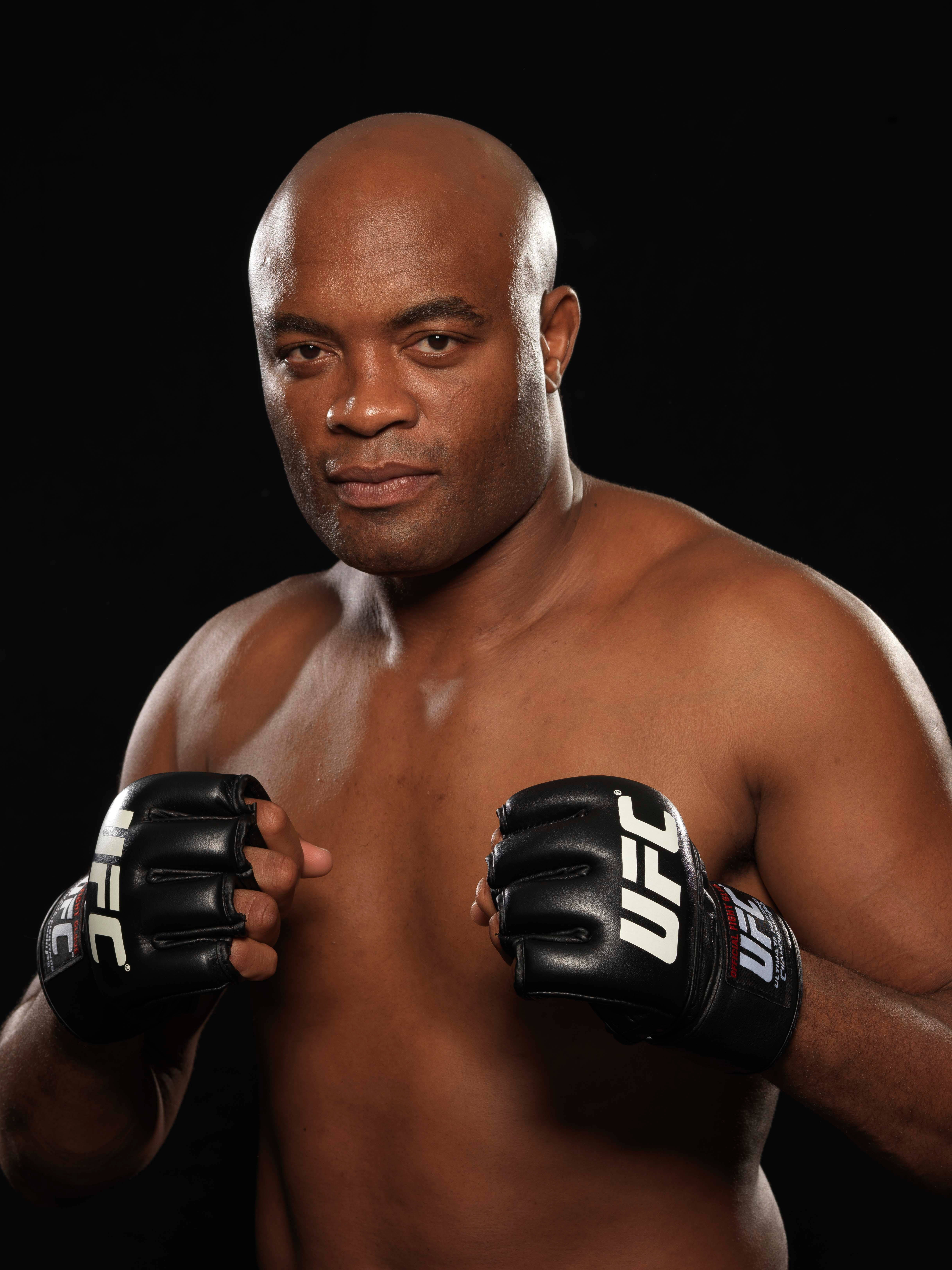 UFC 桌布 壁紙 — 一個肌肉發達的光頭戰士戴著黑色UFC手套，在純黑背景下強烈凝視。