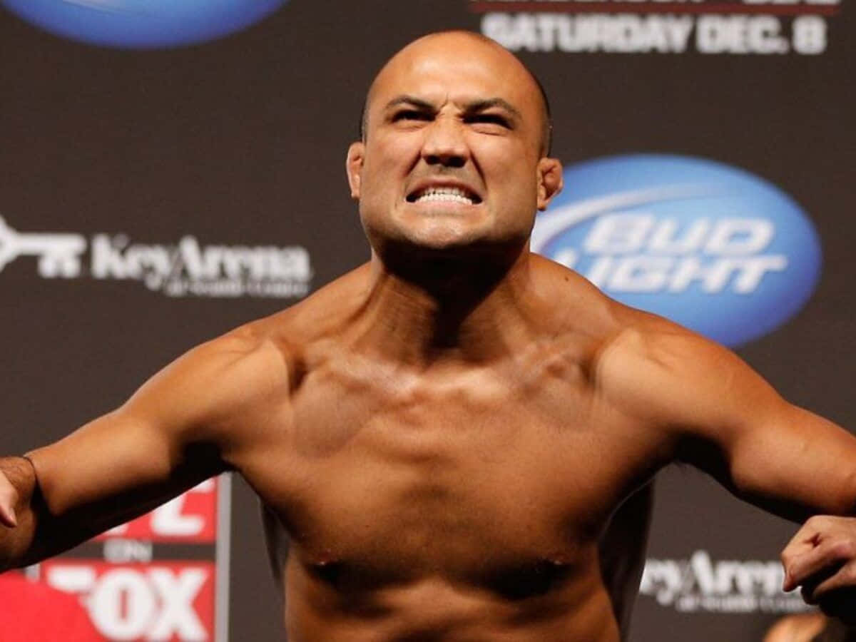 UFC 桌布 壁紙 — 一個肌肉發達的光頭拳手在稱重活動中張開雙臂，表情猙獰。