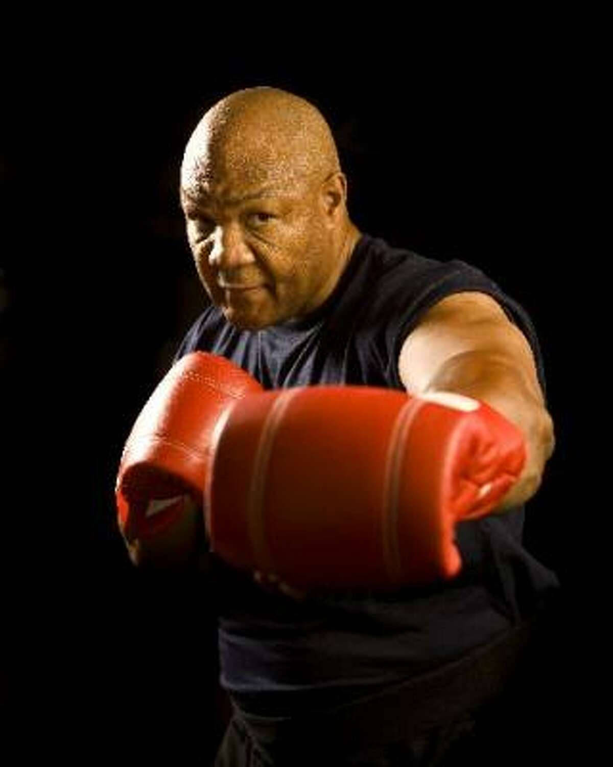 Boxing 桌布 壁紙 — 一個肌肉發達的光頭拳擊手戴著紅色手套，在黑色背景下強烈地向前凝視。