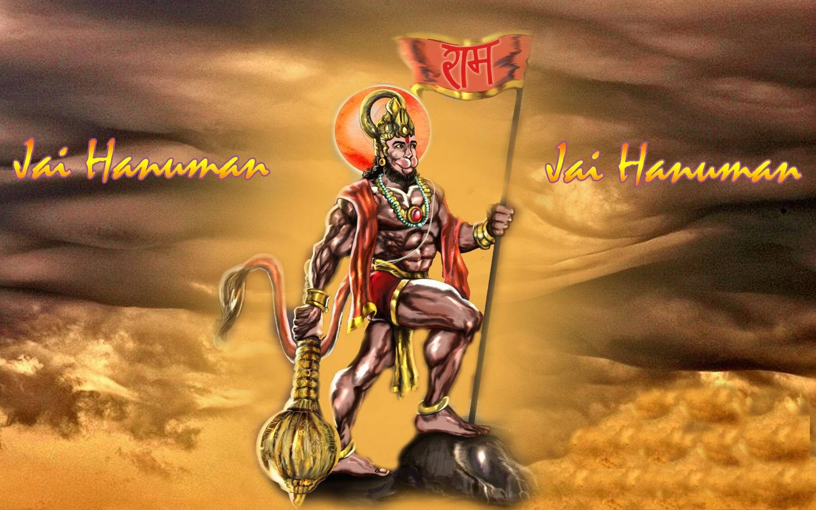 Hanuman 桌布 壁紙 — 一個肌肉發達的哈努曼站在岩石上，手持旗幟和狼牙棒，背景是金色風暴天空，上面有「Jai Hanuman」文字。