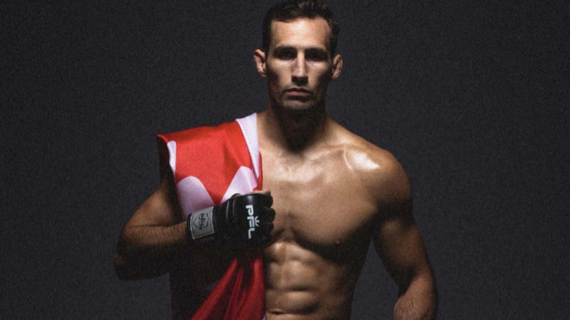 MMA 桌布 壁紙 — 一個肌肉發達的戰士，肩上披著紅白相間的旗幟，自信地站在深色背景前。