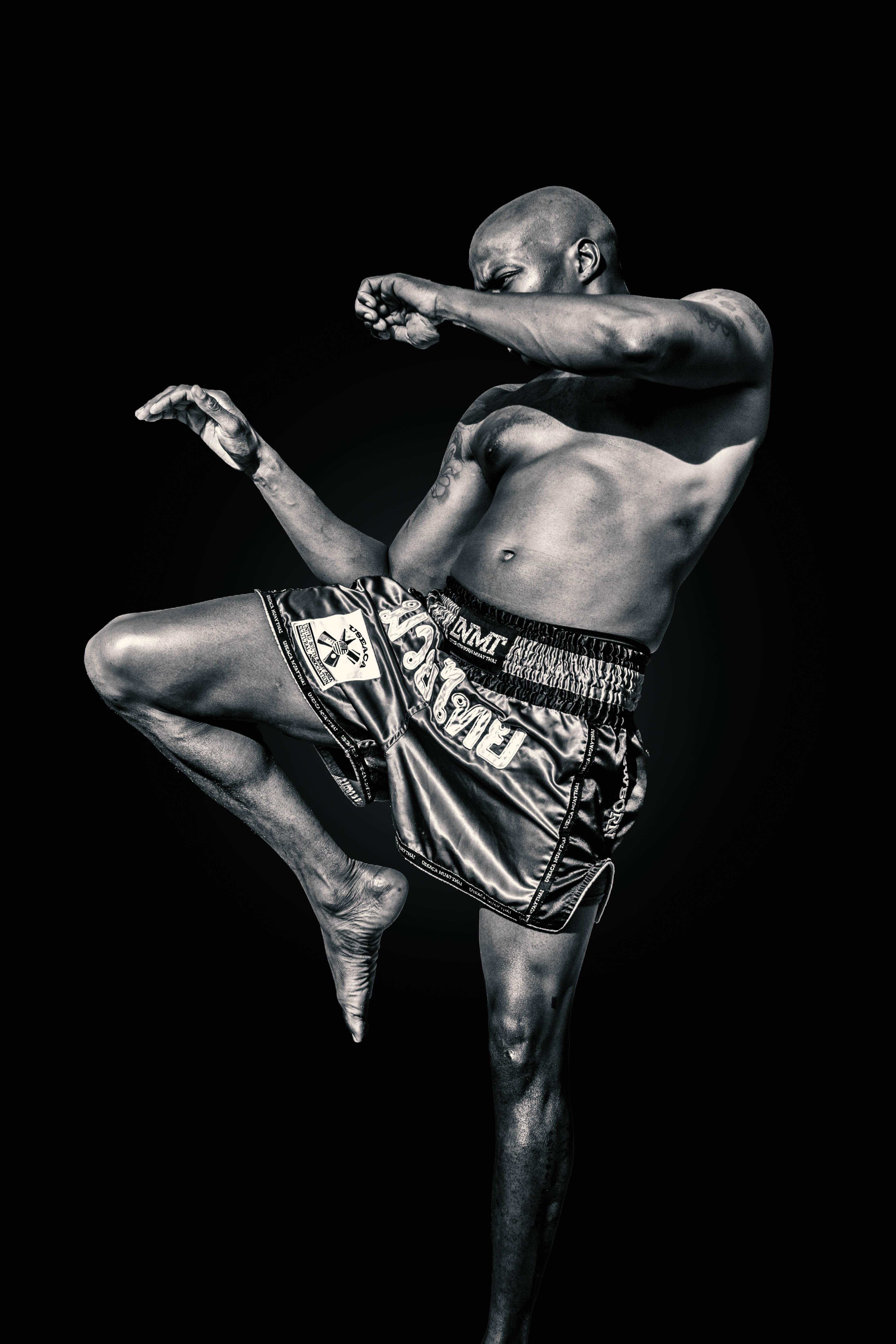 Warrior 桌布 壁紙 — 一個肌肉發達的戰士在黑暗背景下以戲劇性的黑白畫面執行高踢。