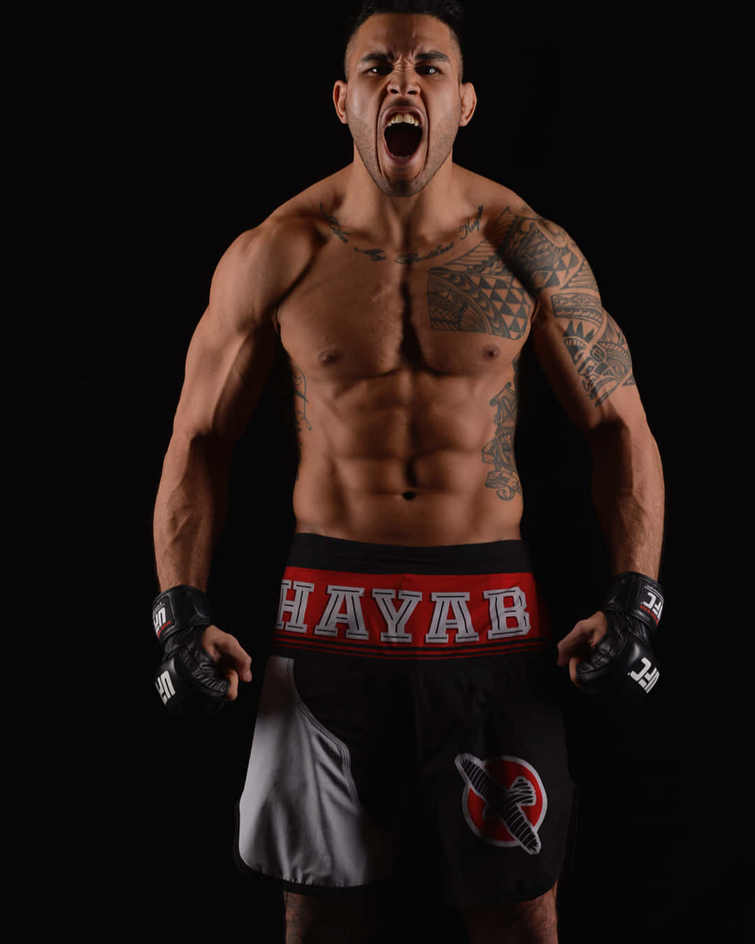 UFC 桌布 壁紙 — 一個肌肉發達的戰士帶有部落紋身，在黑色背景下穿著Hayab短褲和手套，激烈地咆哮。