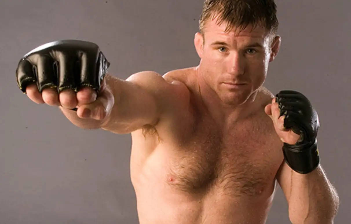 UFC 桌布 壁紙 — 一個肌肉發達的戰士戴著黑色手套，對著純灰色背景猛烈出拳，眼神專注。