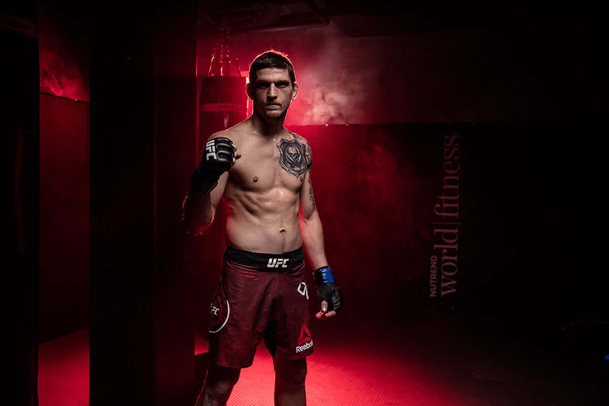 UFC 桌布 壁紙 — 一個肌肉發達的戰士穿著UFC短褲，自信地站在昏暗的健身房中，被紅光籠罩，煙霧在他周圍旋轉。