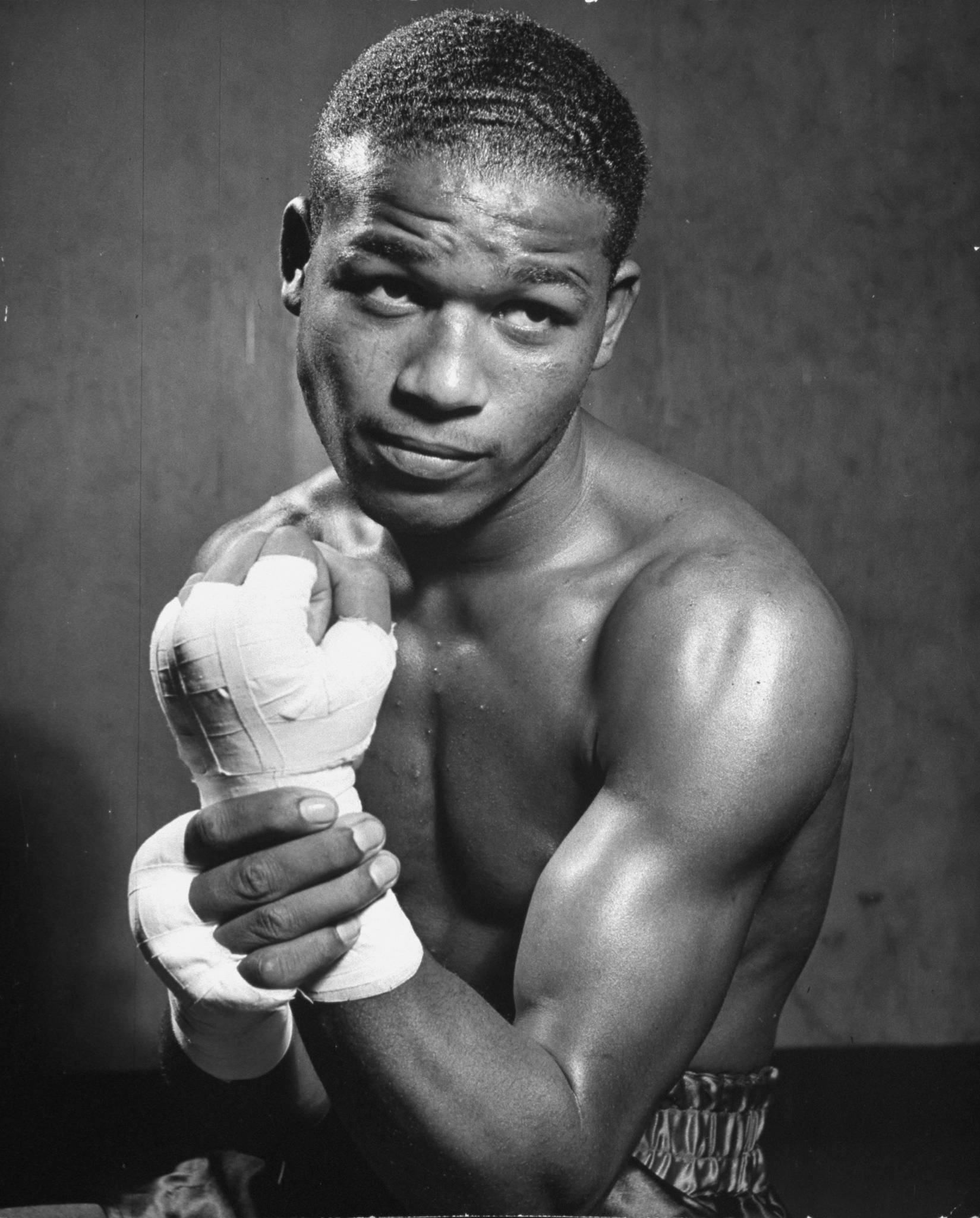 Boxing 桌布 壁紙 — 一個肌肉發達的拳擊手，雙手纏著繃帶，在黑白肖像中強烈地凝視著鏡頭。