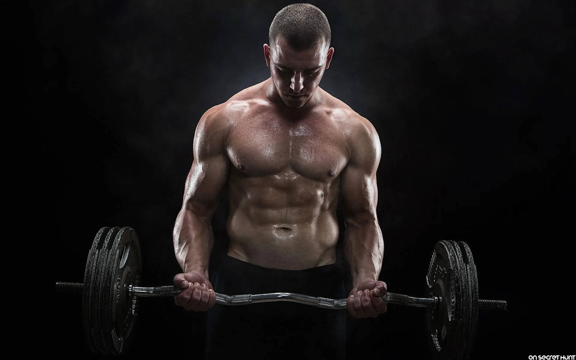 Barbell 桌布 壁紙 — 一個肌肉發達的男人，汗水在軀幹上閃閃發光，在黑暗煙霧繚繞的背景中緊握著沉重的槓鈴。