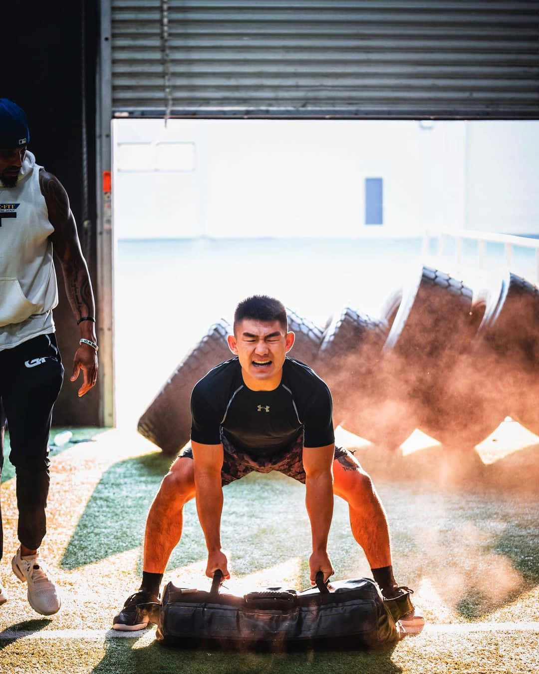 Weight Lifting 桌布 壁紙 — 一個肌肉發達的男人在明亮的陽光下，於粗糙的戶外健身房中咬緊牙關拖著一個沉重的輪胎。