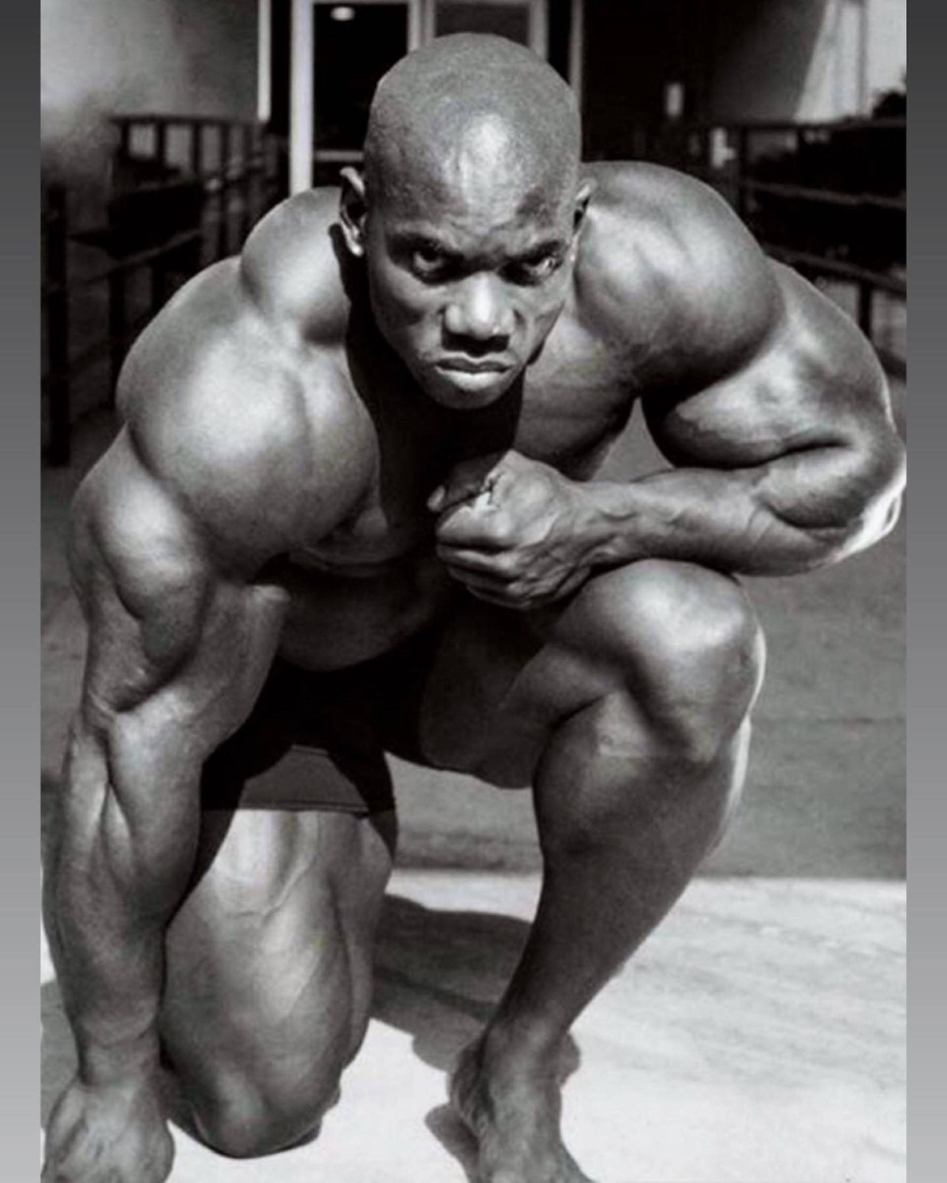 flex wheeler 桌布 壁紙 — 一個肌肉發達的男人在深蹲姿勢的黑白肖像，眼神凌厲。