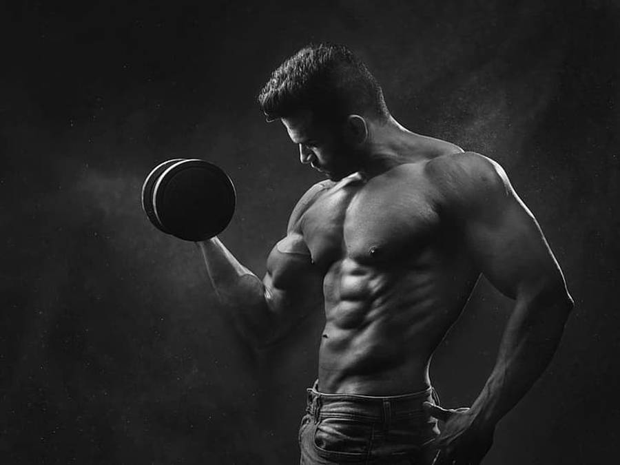 Exercise 桌布 壁紙 — 一個肌肉發達的男人在黑白畫面中，於煙霧瀰漫的黑暗背景下，專注地舉起啞鈴。
