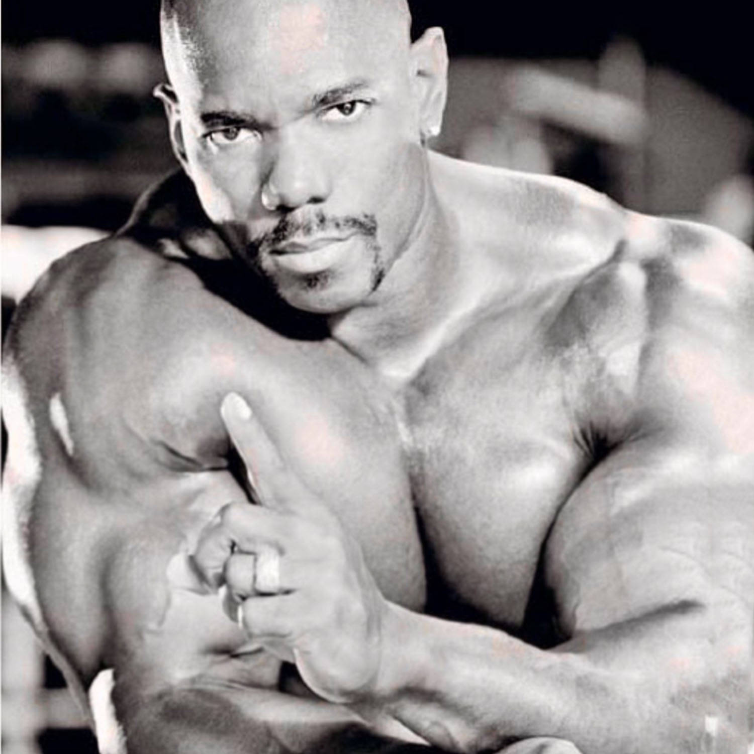 flex wheeler 桌布 壁紙 — 一個肌肉發達的男人在黑白畫面中用力彎曲二頭肌，手指上戴著戒指，眼神專注。