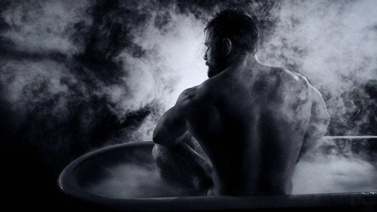 Bathtub 桌布 壁紙 — 一個肌肉發達的男人坐在冒著蒸汽的浴缸中，被旋轉的霧氣包圍，在戲劇性的黑白燈光下。