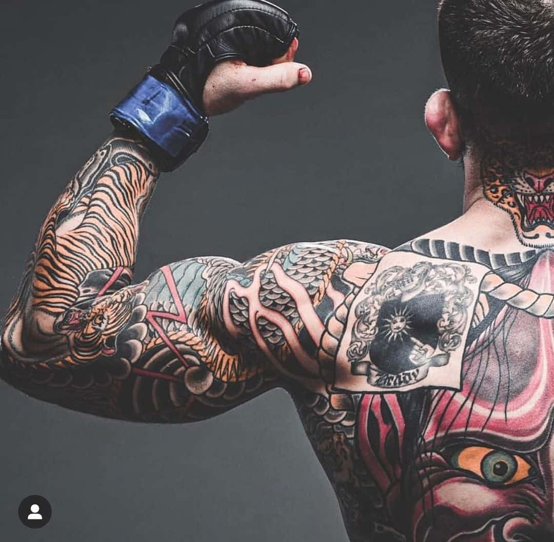 Tattoo 桌布 壁紙 — 一個肌肉發達的男人彎曲他帶有刺青的手臂，展示精緻的傳統日本設計，包括老虎和魔鬼面孔，背景是深色攝影棚。