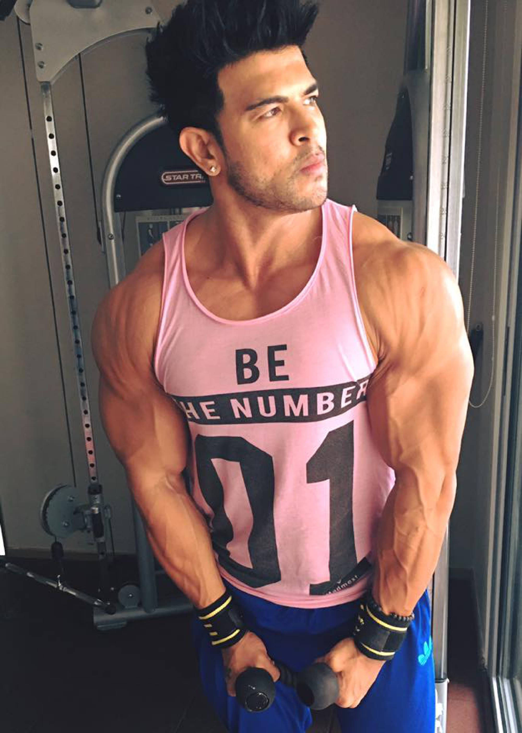 Fitness 桌布 壁紙 — 一個肌肉發達的男人穿著粉紅色背心，在健身房舉著啞鈴彎曲手臂。